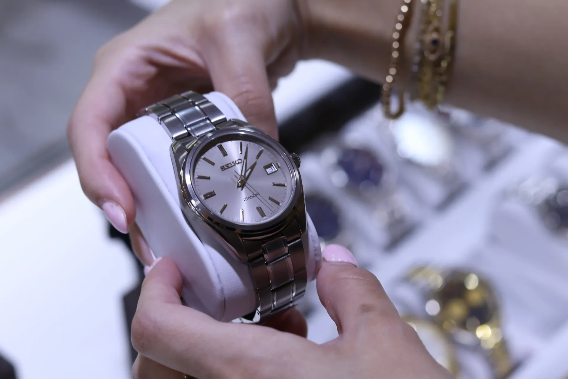 A woman is holding a silver watch in her hands.