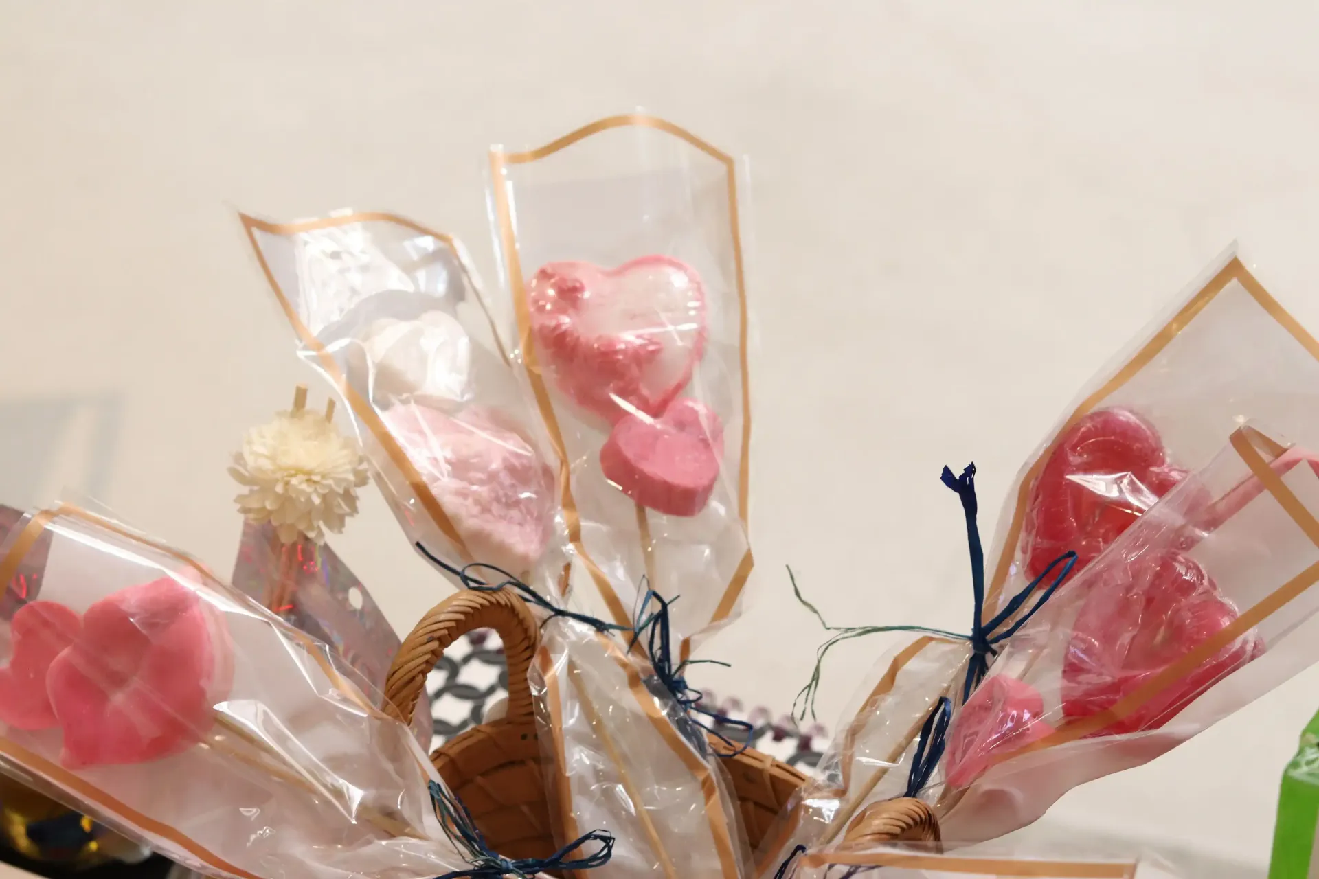 A basket overflowing with heart-shaped lollipops in clear wrappers.