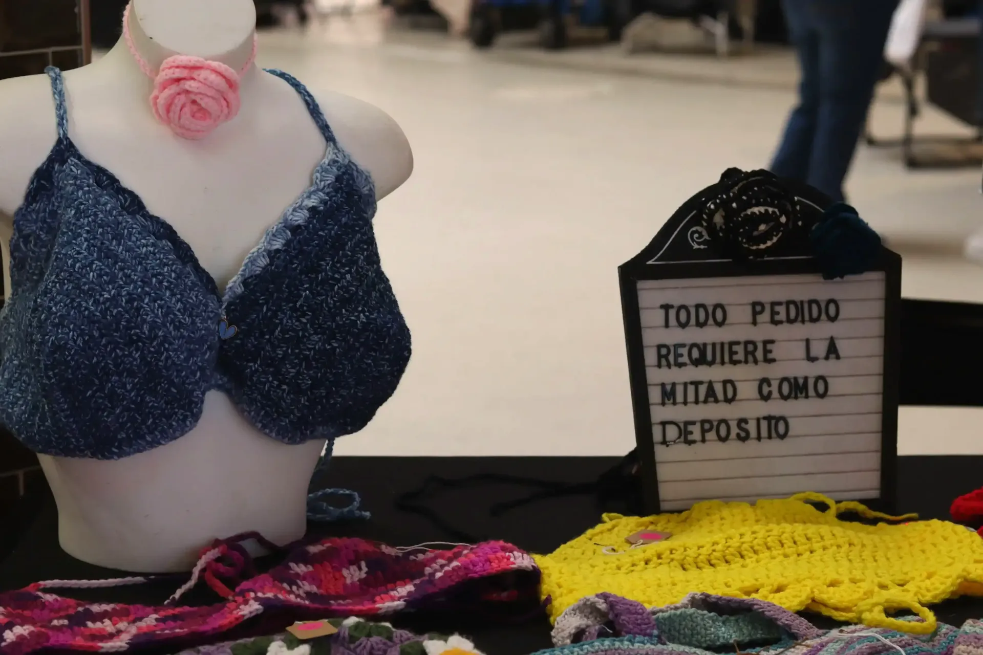 A mannequin bust displaying a crocheted blue bra with a pink flower, in Céntrico Guayama
