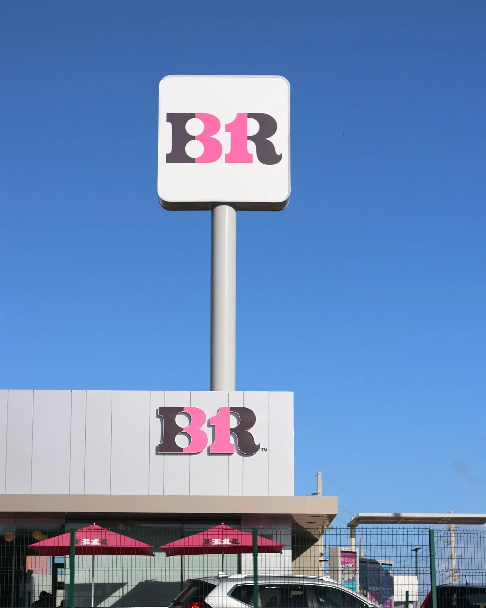 Baskin-Robbins store sign against a clear blue sky. White sign with pink and brown 