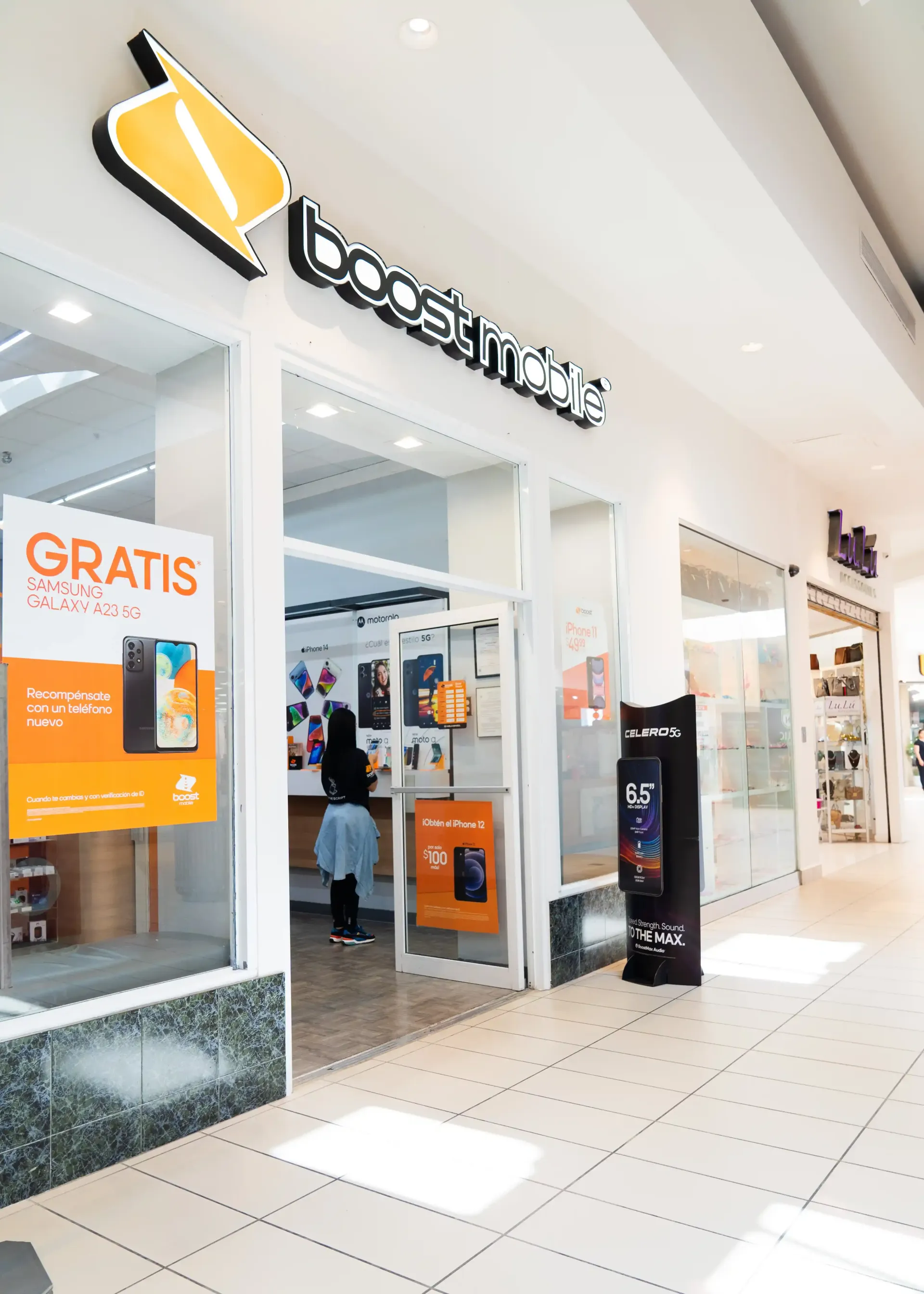 Boost Mobile store in a mall with a person inside. Orange and black signage.
