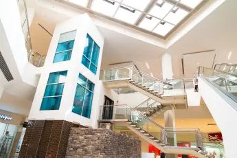 Modern mall interior with a stone-clad structure and stairs leading upward.