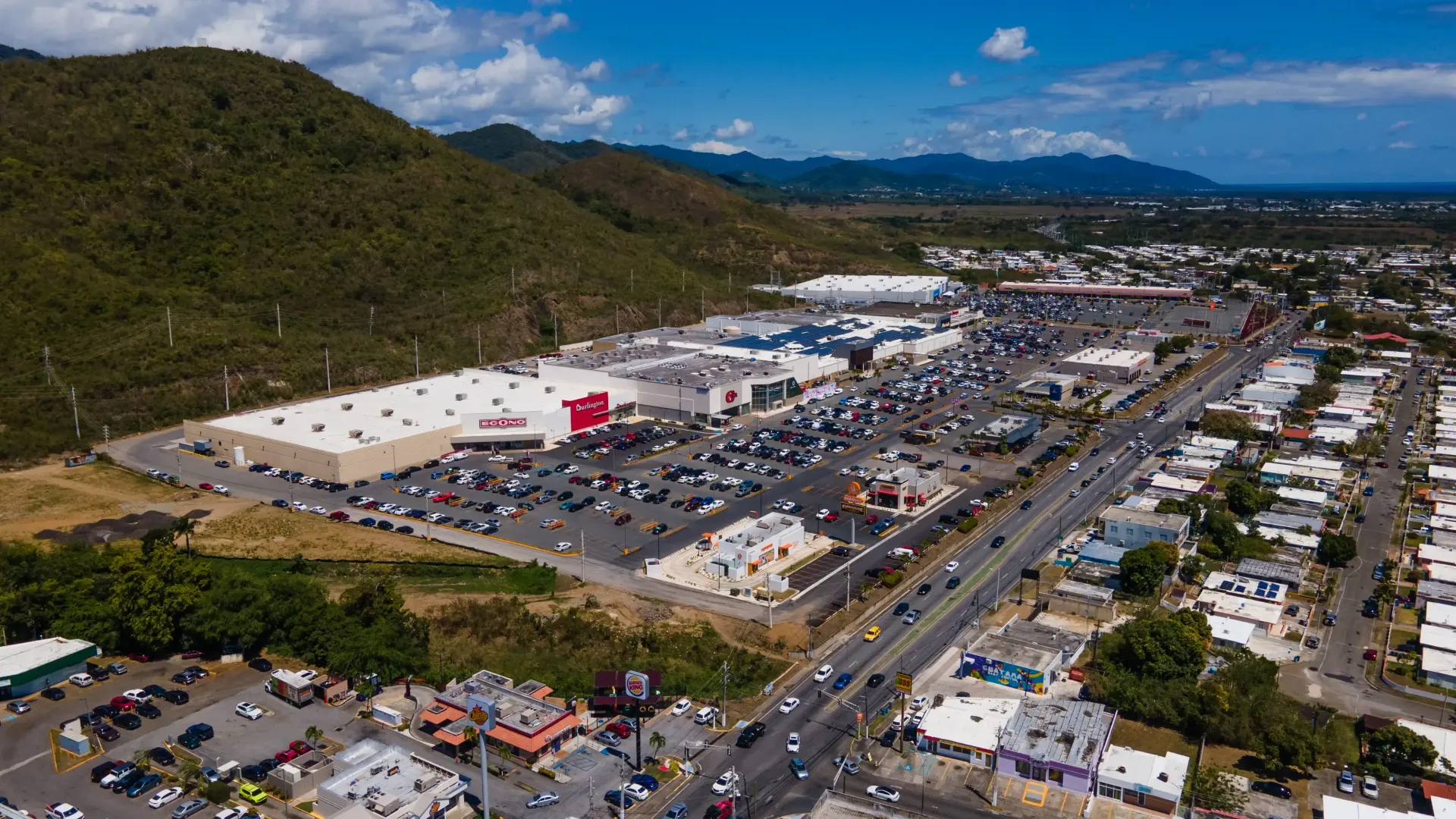 Aerial view of Céntrico Guayama with a large parking lot filled with cars.