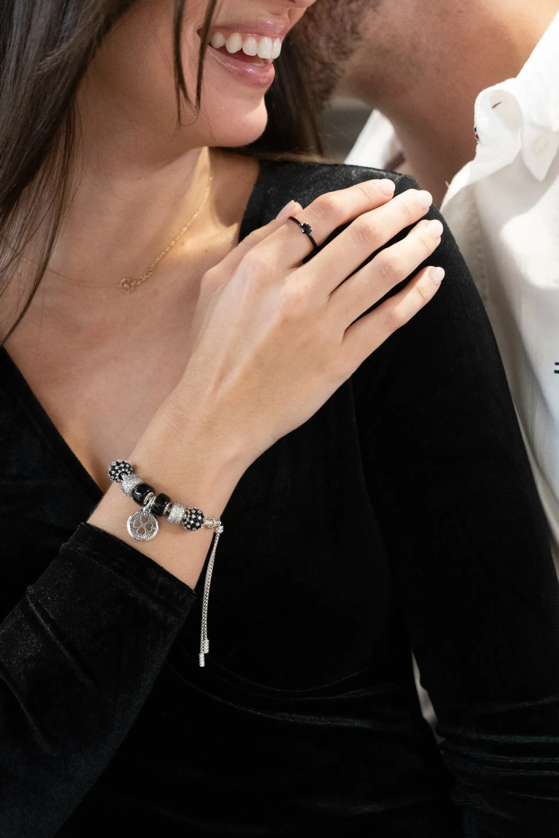 A woman wearing a bracelet and a ring is hugging a man.