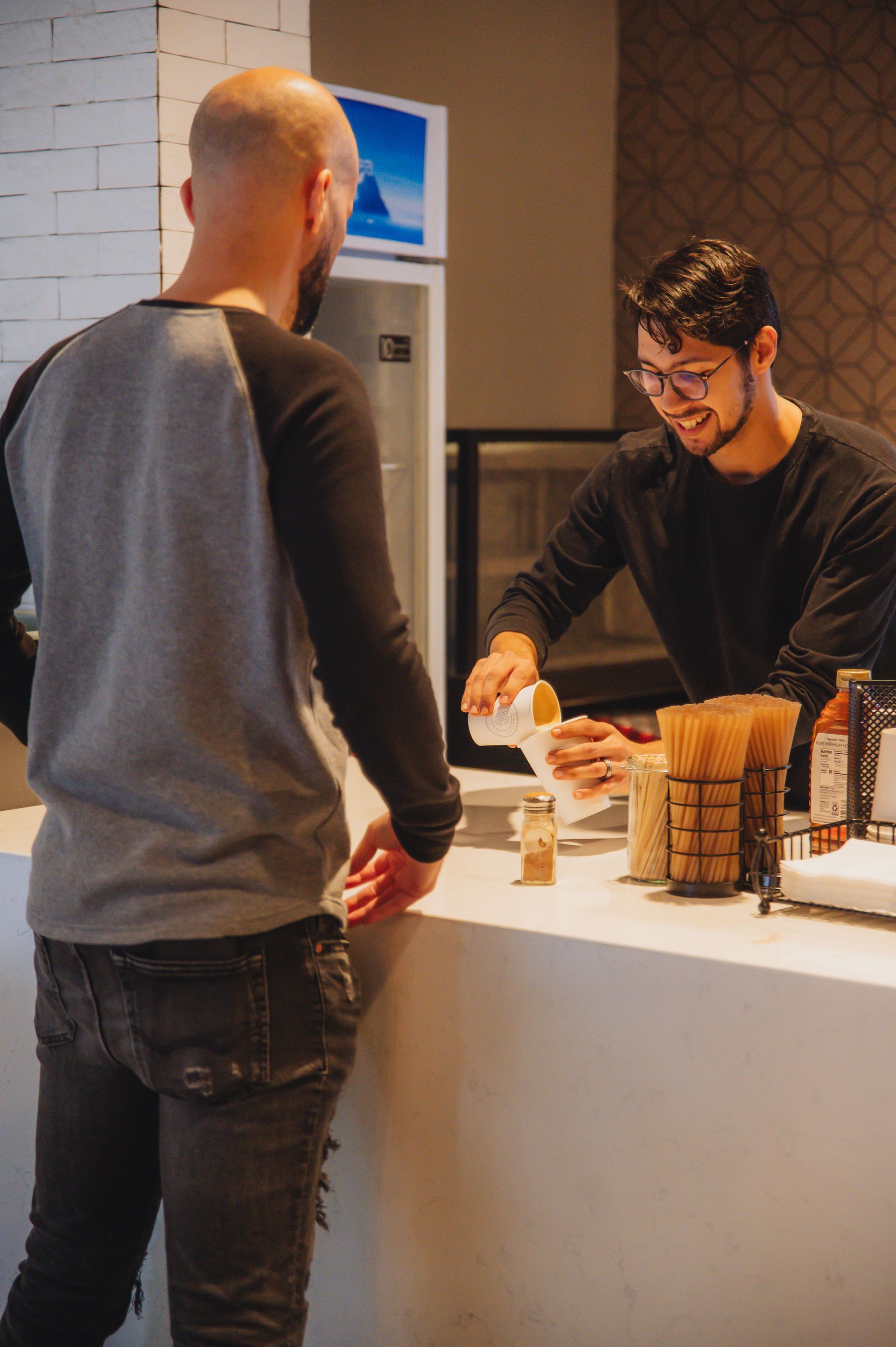 A man is standing at a counter talking to another man.