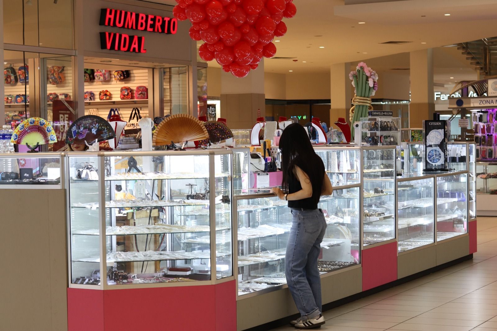 A woman is standing in front of a display case in a store.