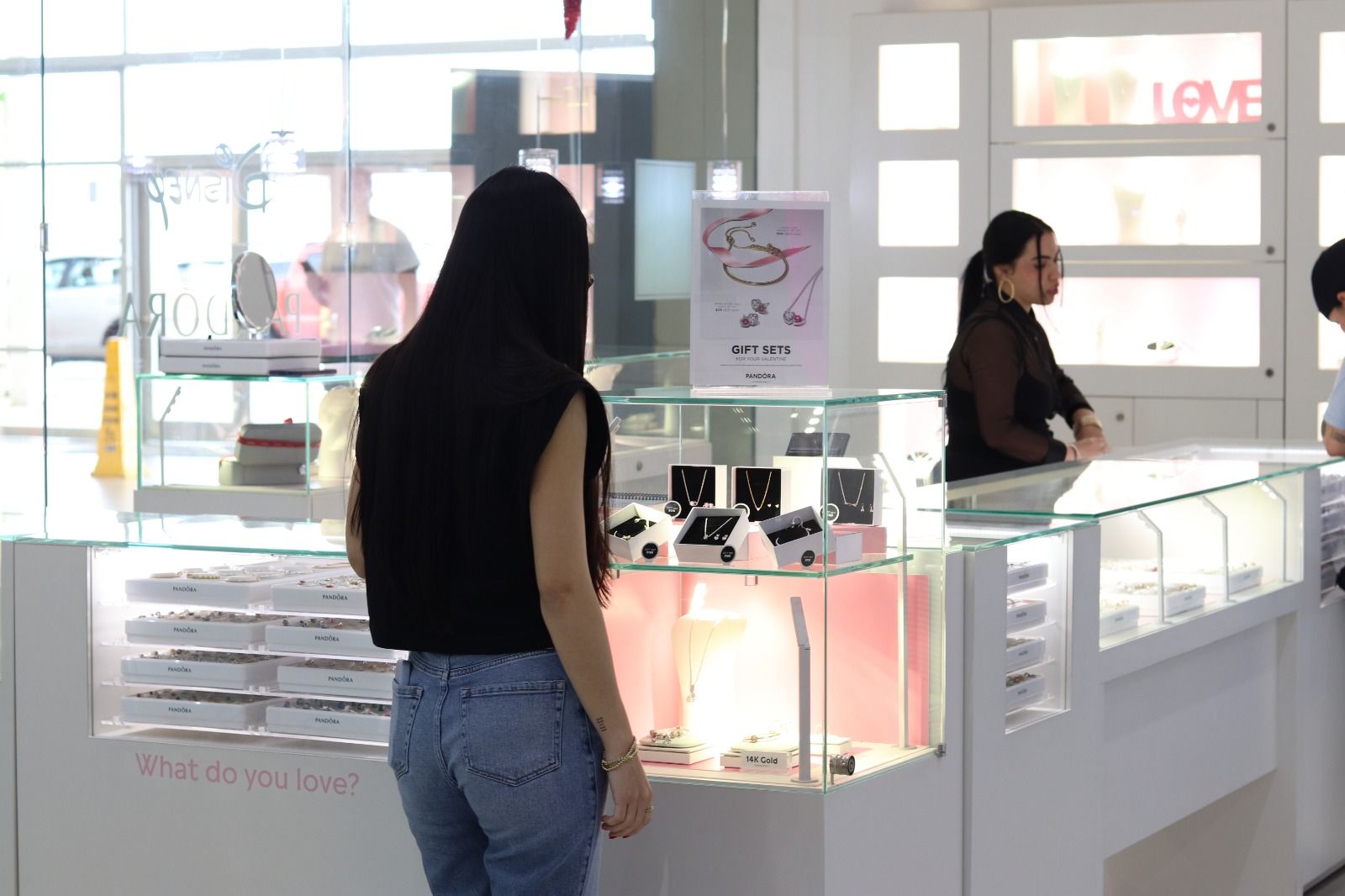 A woman is standing in front of a display case in a jewelry store.
