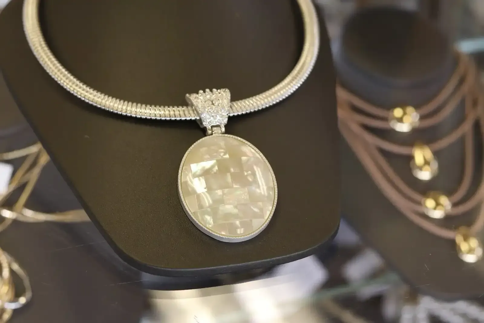 A necklace with a round pendant is on a mannequin