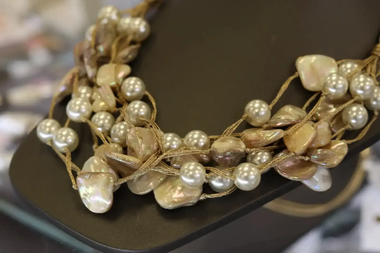 A close up of a necklace with pearls on a mannequin.