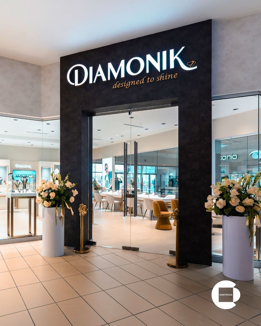DIAMONIK jewelry store entrance in a mall, with floral displays and a black storefront sign