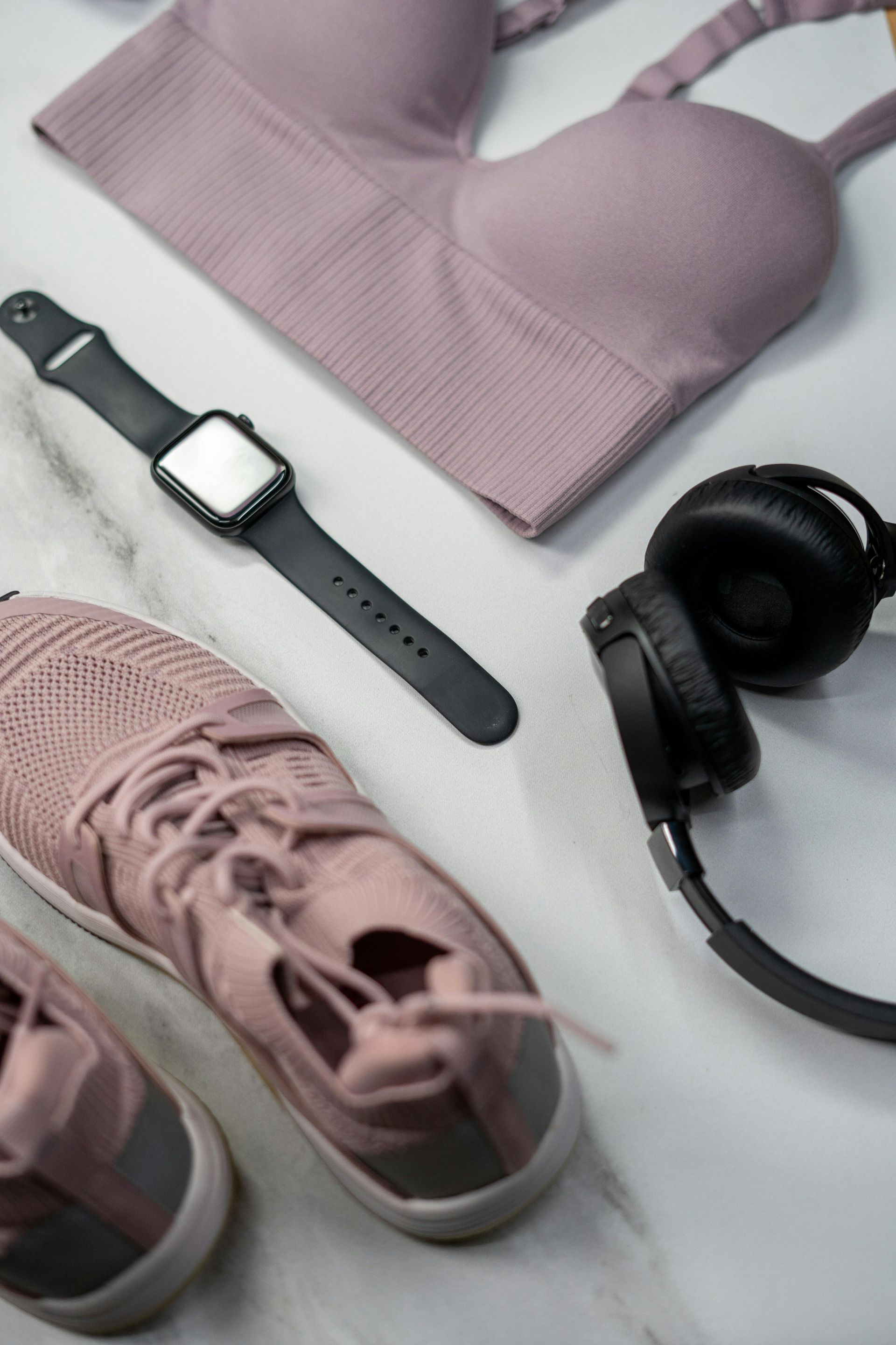 A watch , headphones , a bra , and a pair of pink shoes are on a table.