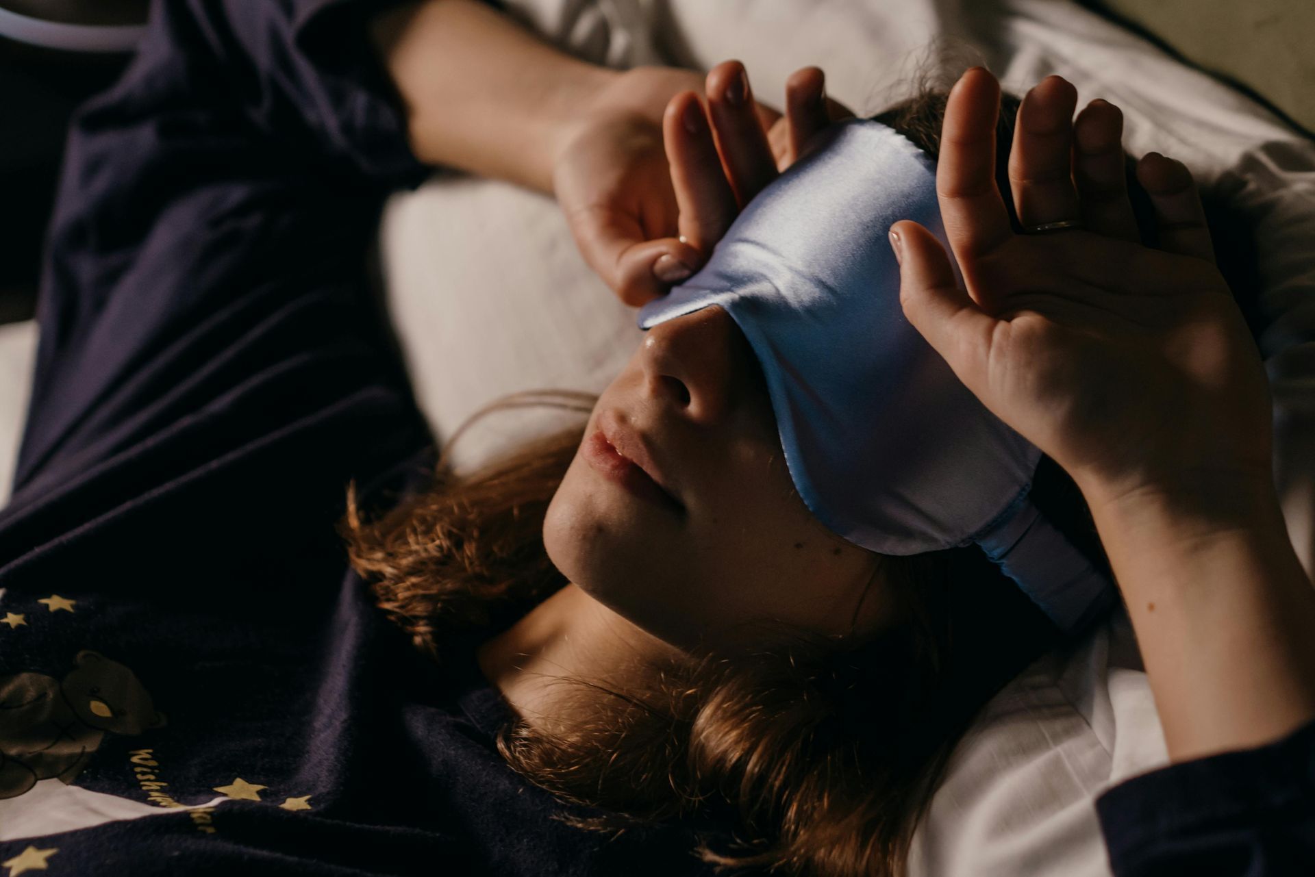 A woman is laying in bed with a sleep mask on her eyes.