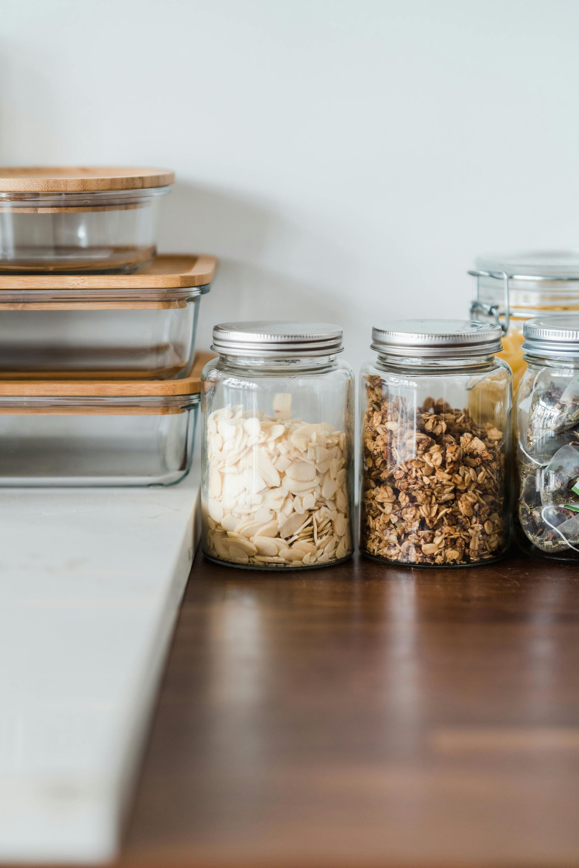 There are many jars of food on the counter.