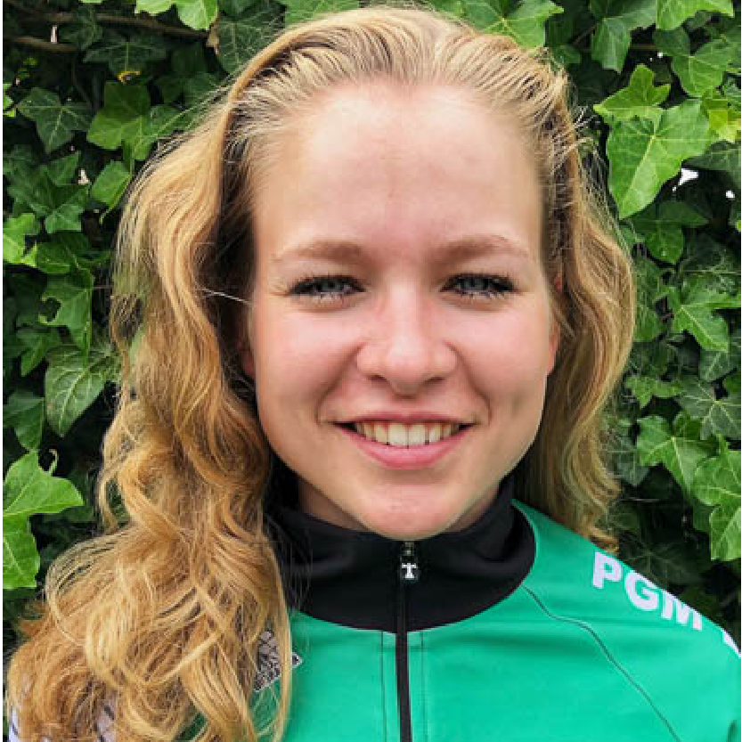 Een glimlachend persoon in een groene jas voor een groene achtergrond.