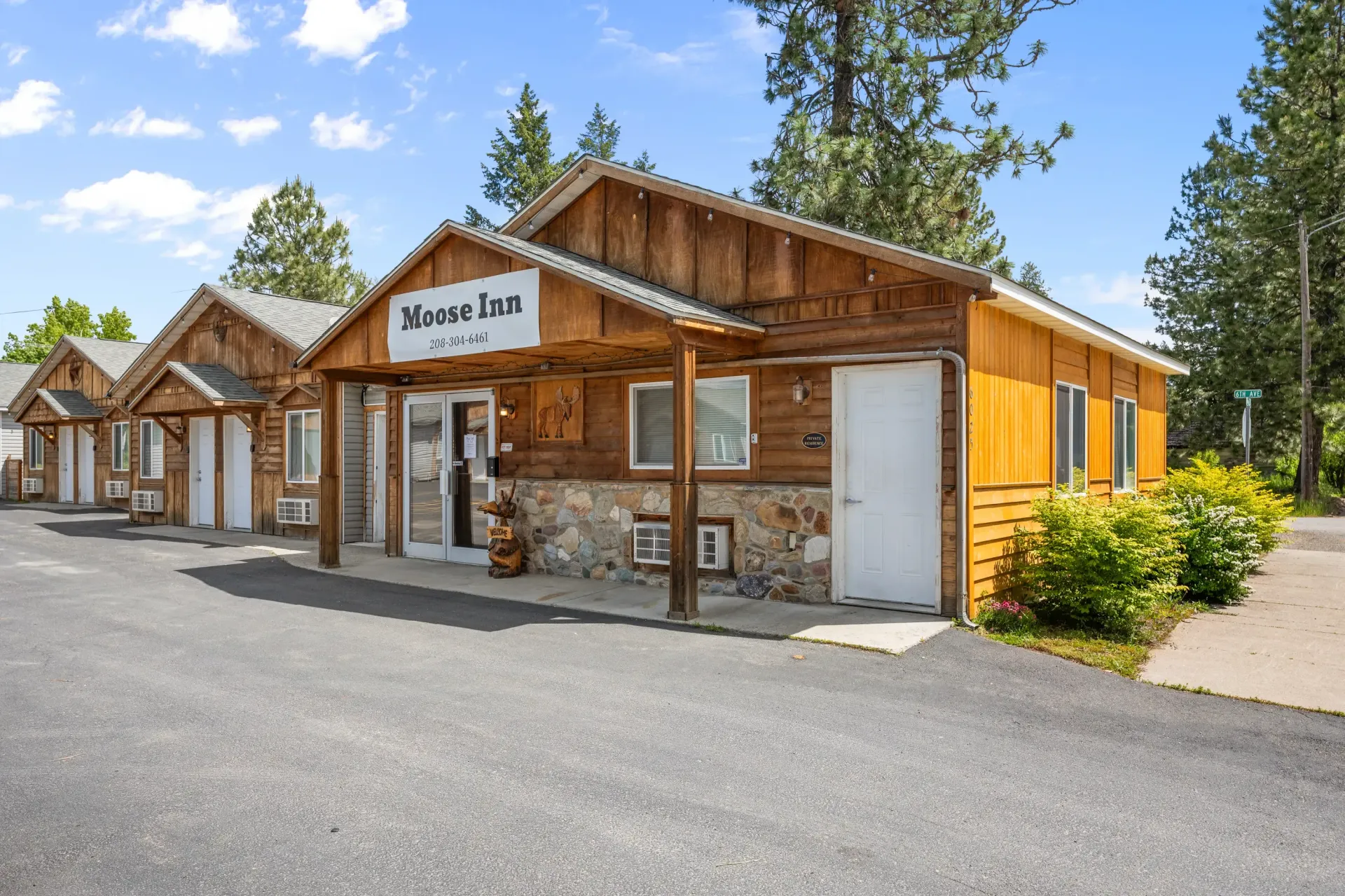 A small wooden building with a lot of windows and doors is surrounded by trees.