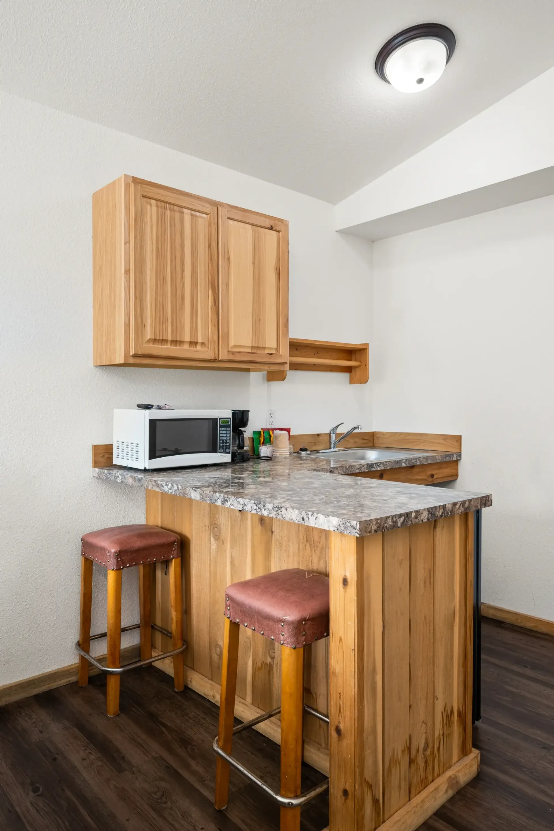A small kitchen with a microwave , sink , and wooden cabinets.