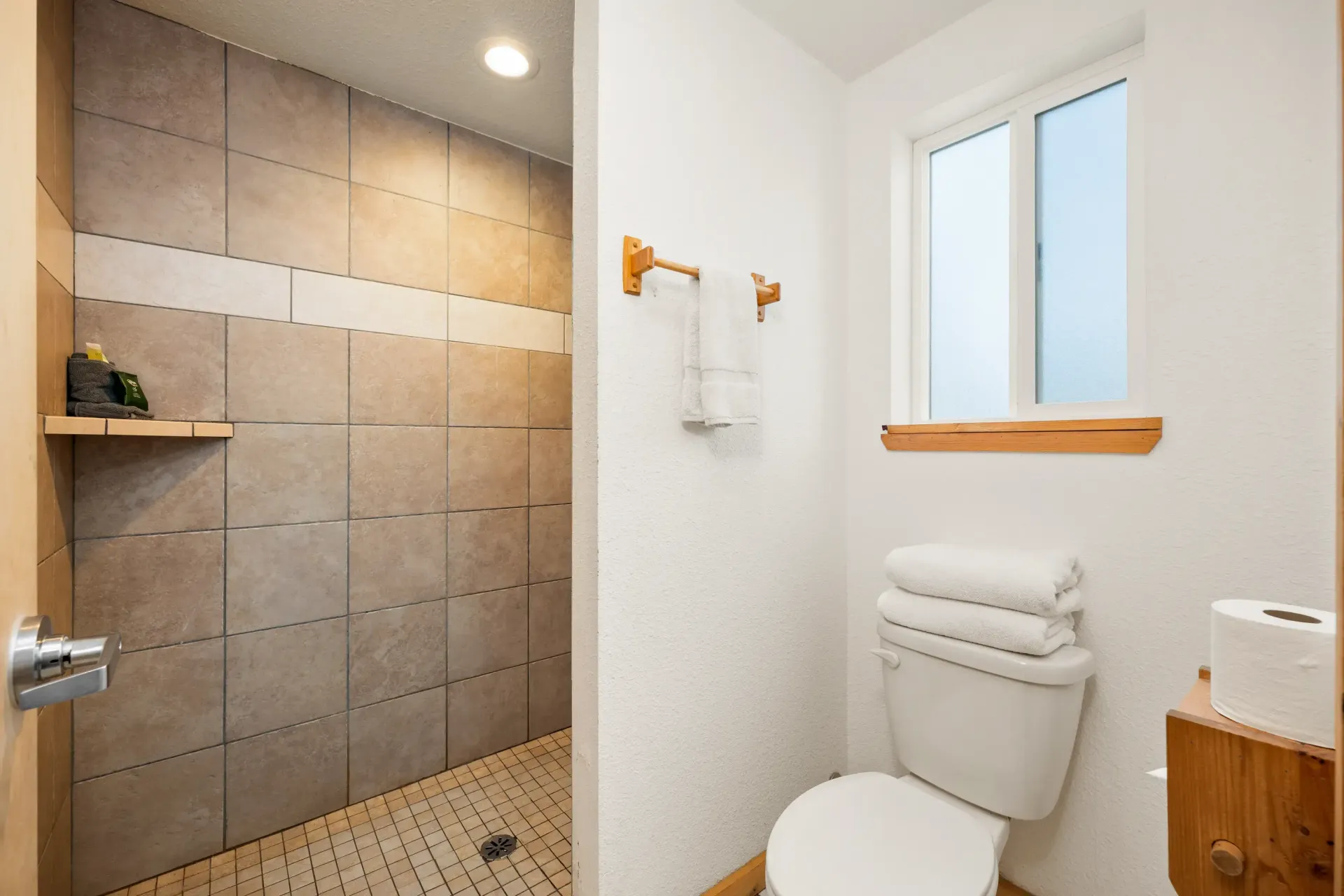 A bathroom with a toilet , shower and window