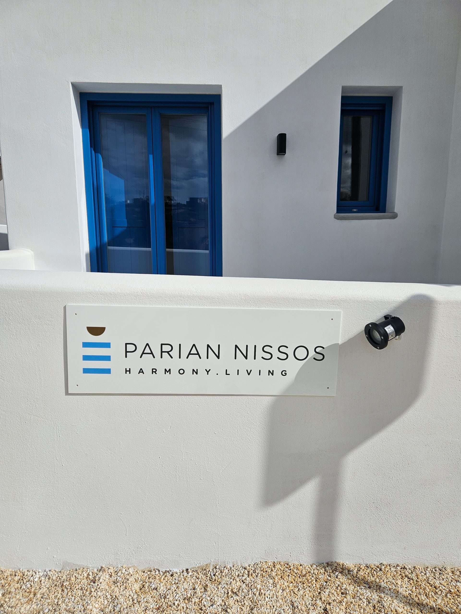 White building with blue doors and windows. Sign reads 