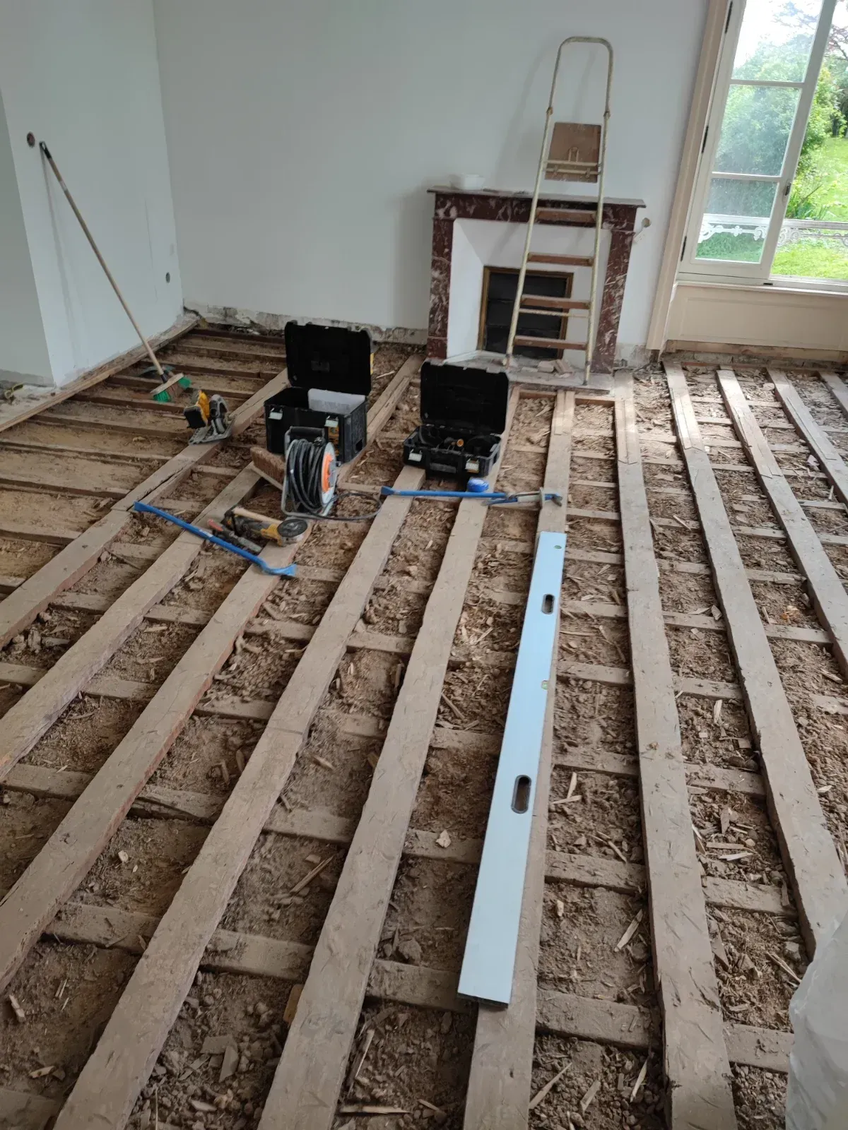 Avant travaux : solives et lambourdes anciennes mises à nu devant la cheminée en marbre