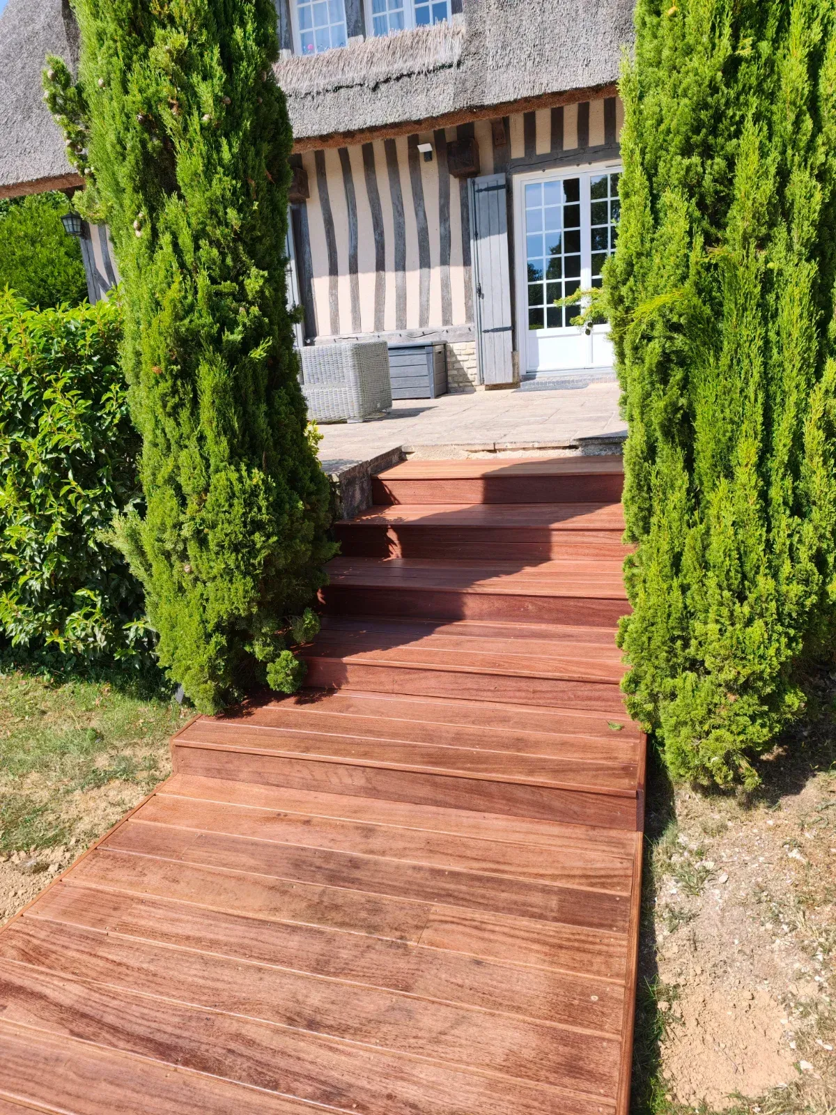 Escalier extérieur en bois exotique devant une chaumière normande