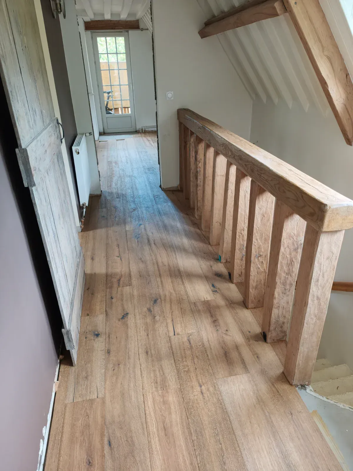 Parquet en chêne brossé posé dans un couloir avec garde-corps en chêne massif