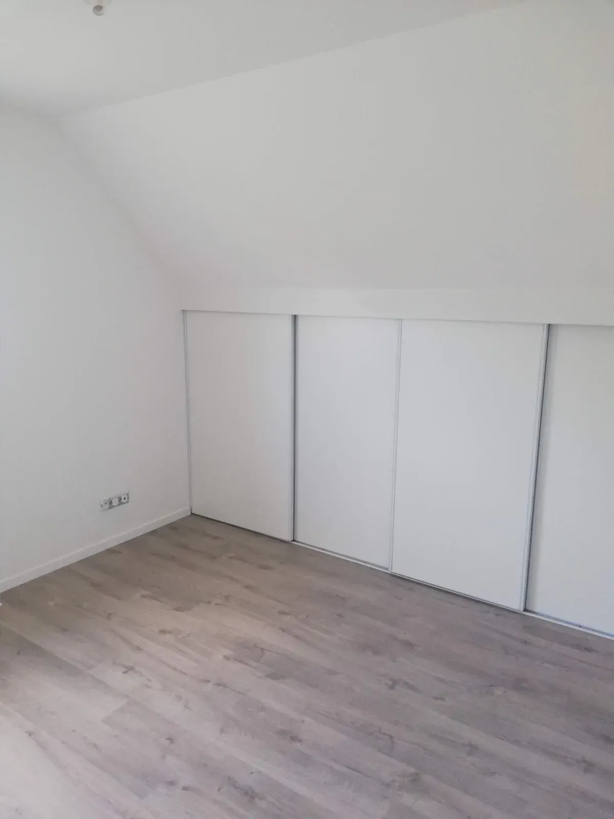 Placard sur mesure à portes coulissantes sous les combles, avec sol posé dans la foulée