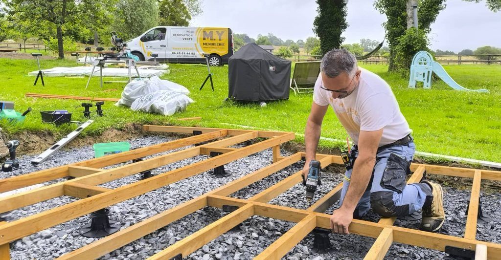 Yoann Lavolo fixe les lambourdes en bois exotique sur des plots réglables avant la pose des lames de terrasse