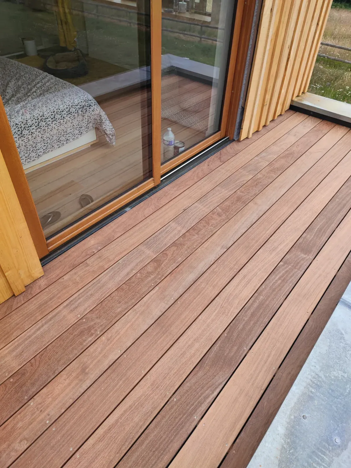 Terrasse en ipé devant une baie coulissante, teinte brun olive