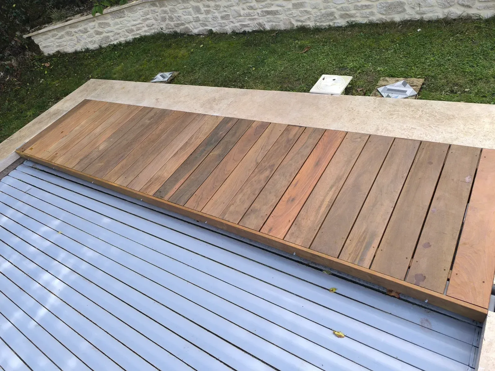 Lame de terrasse en bois exotique au-dessus d'un volet de piscine