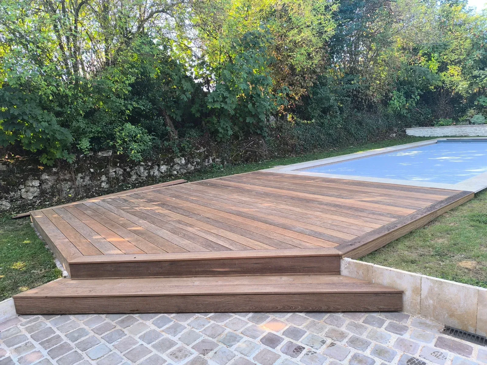 Plage de piscine en bois exotique avec lames posées en diagonale