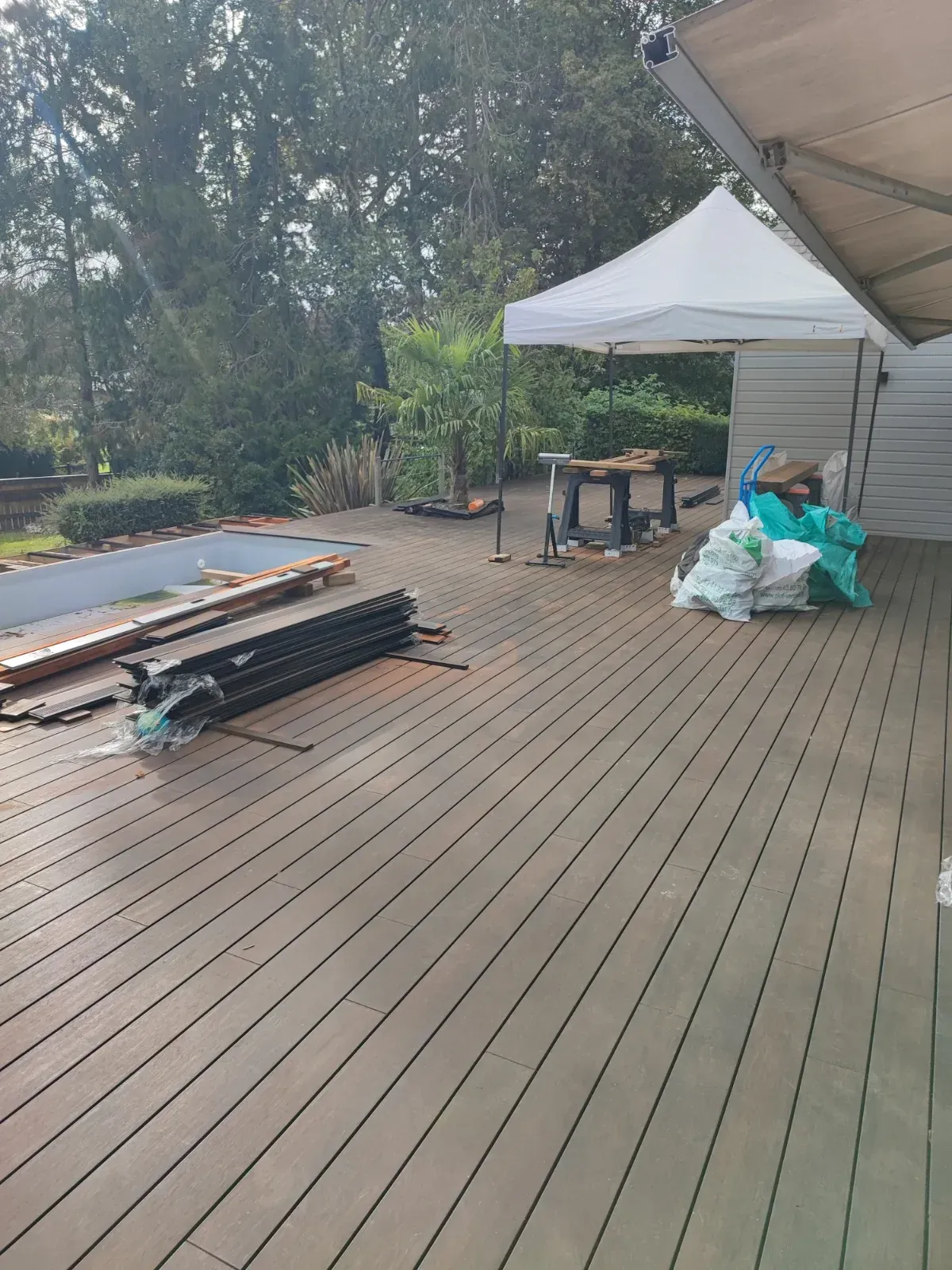 Terrasse en lames composite en cours de pose autour d'un bassin