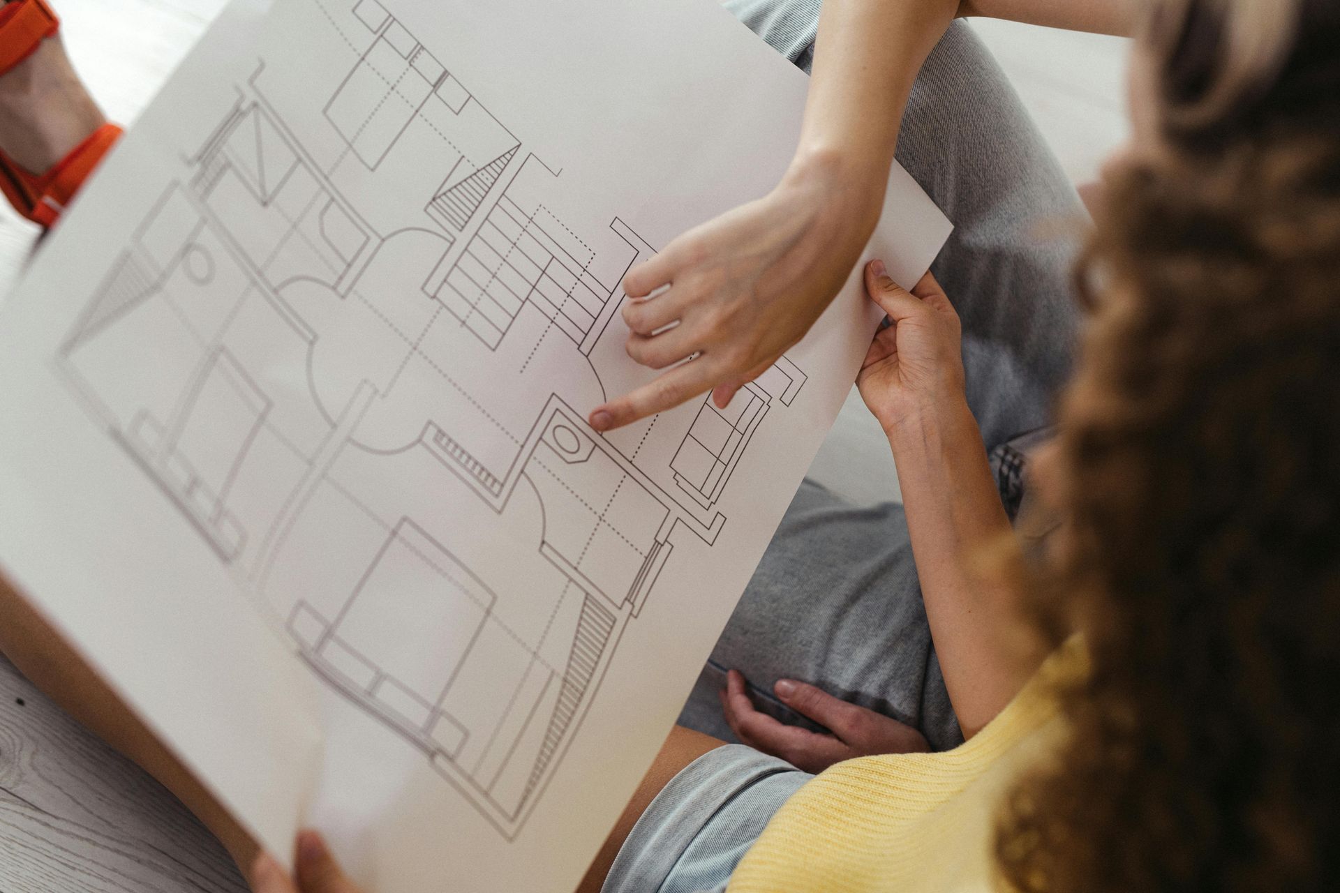 Two people looking at and pointing at architectural blueprints.
