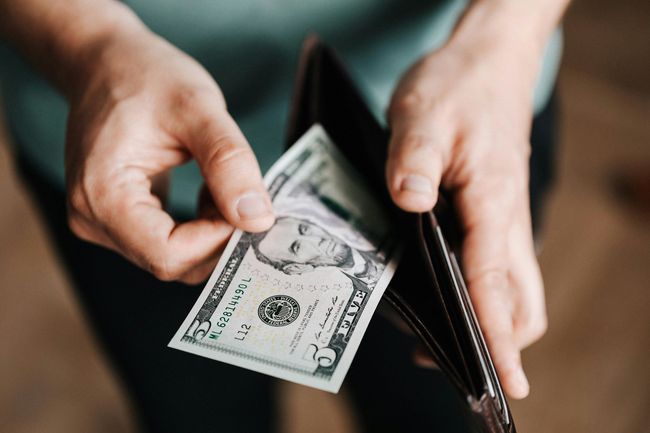 A person is taking a dollar bill out of their wallet.
