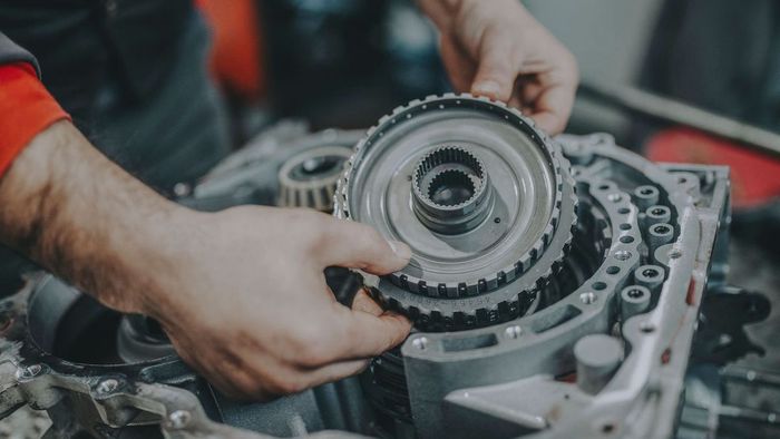 A man is working on a gearbox in a garage.