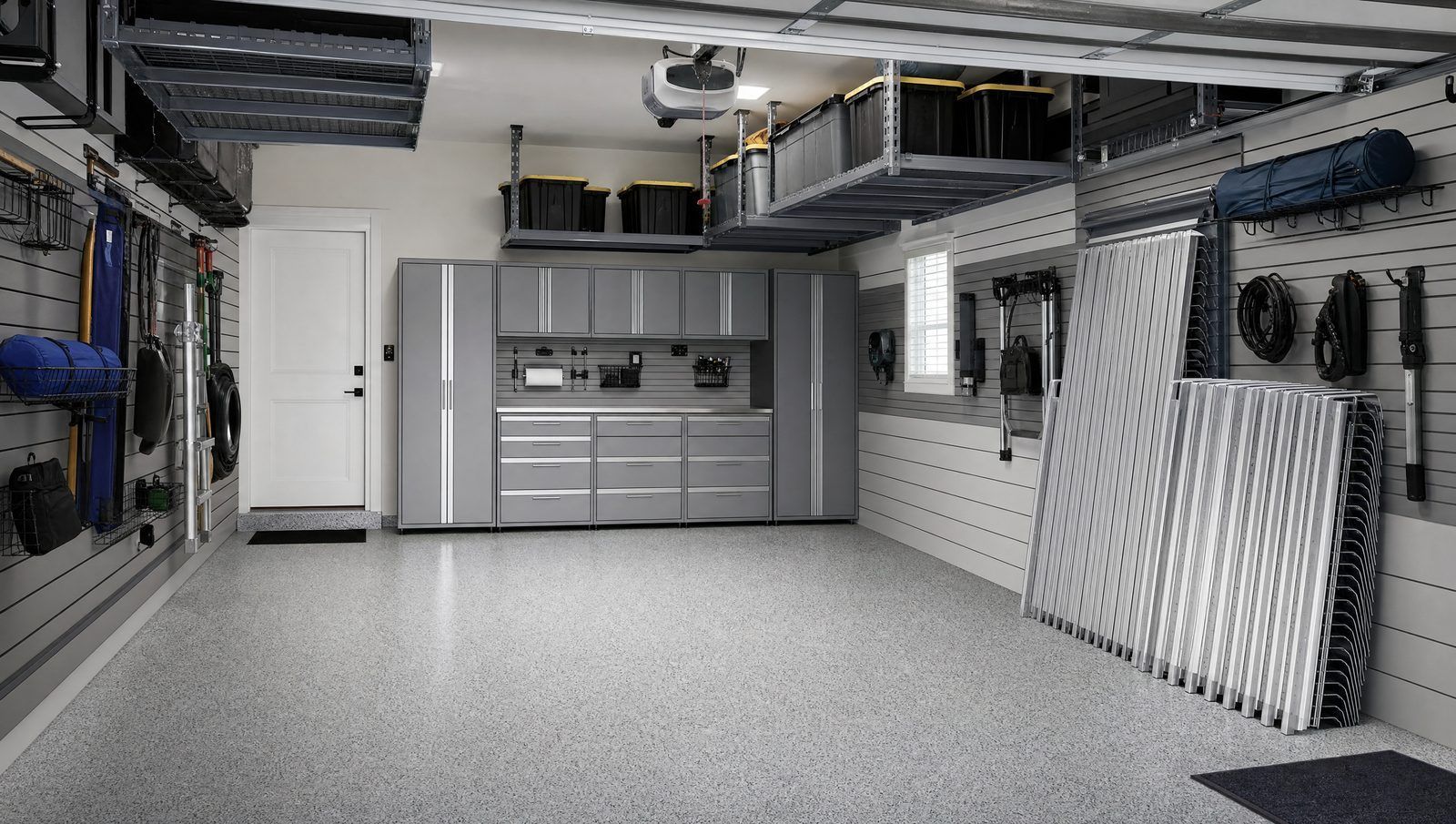 Organized garage with slatwall storage, ceiling racks, and stacked storm shutter panels
