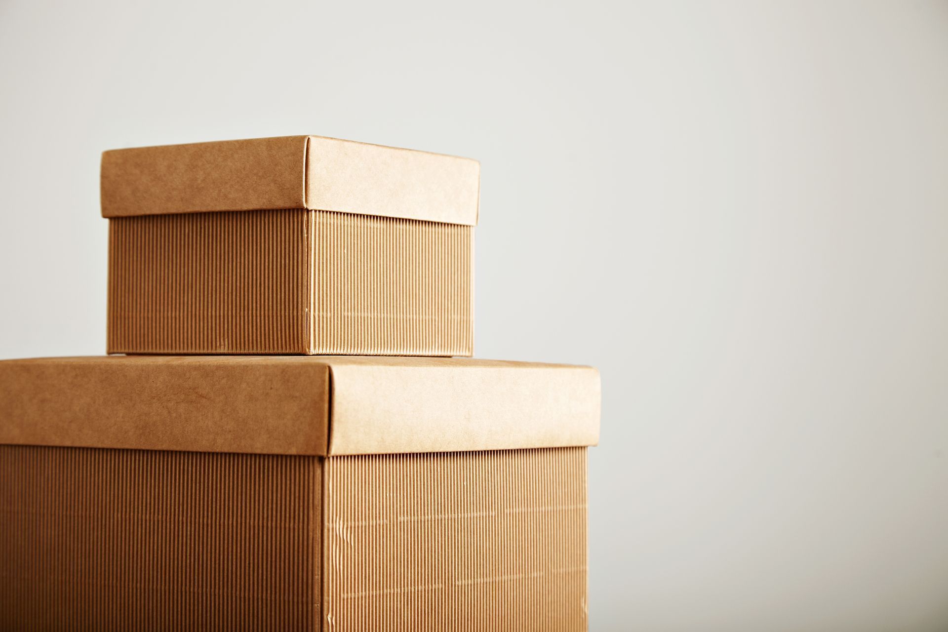 Dos cajas de cartón marrón apiladas sobre un fondo gris claro.