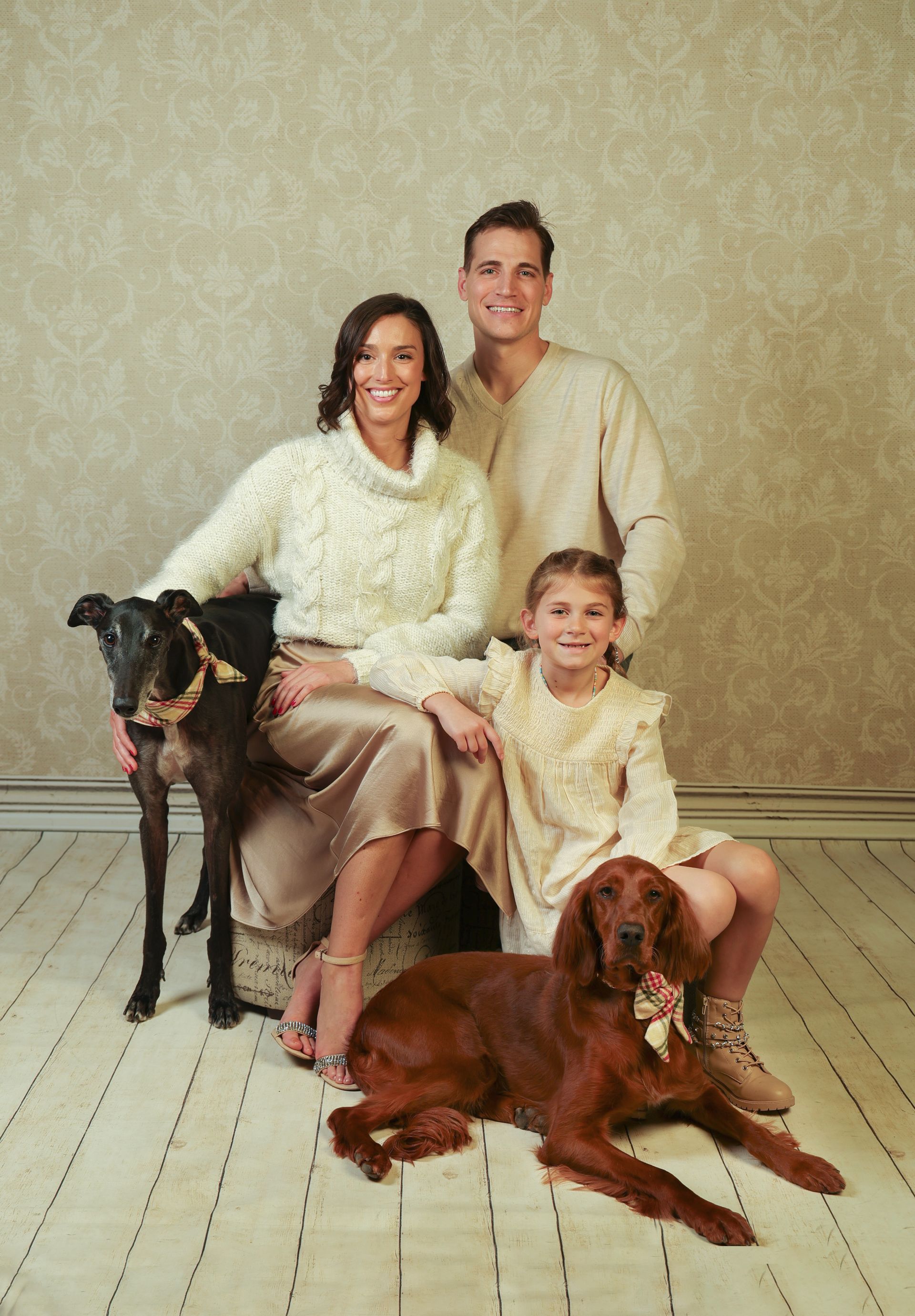 A family is posing for a family portrait with two dogs .