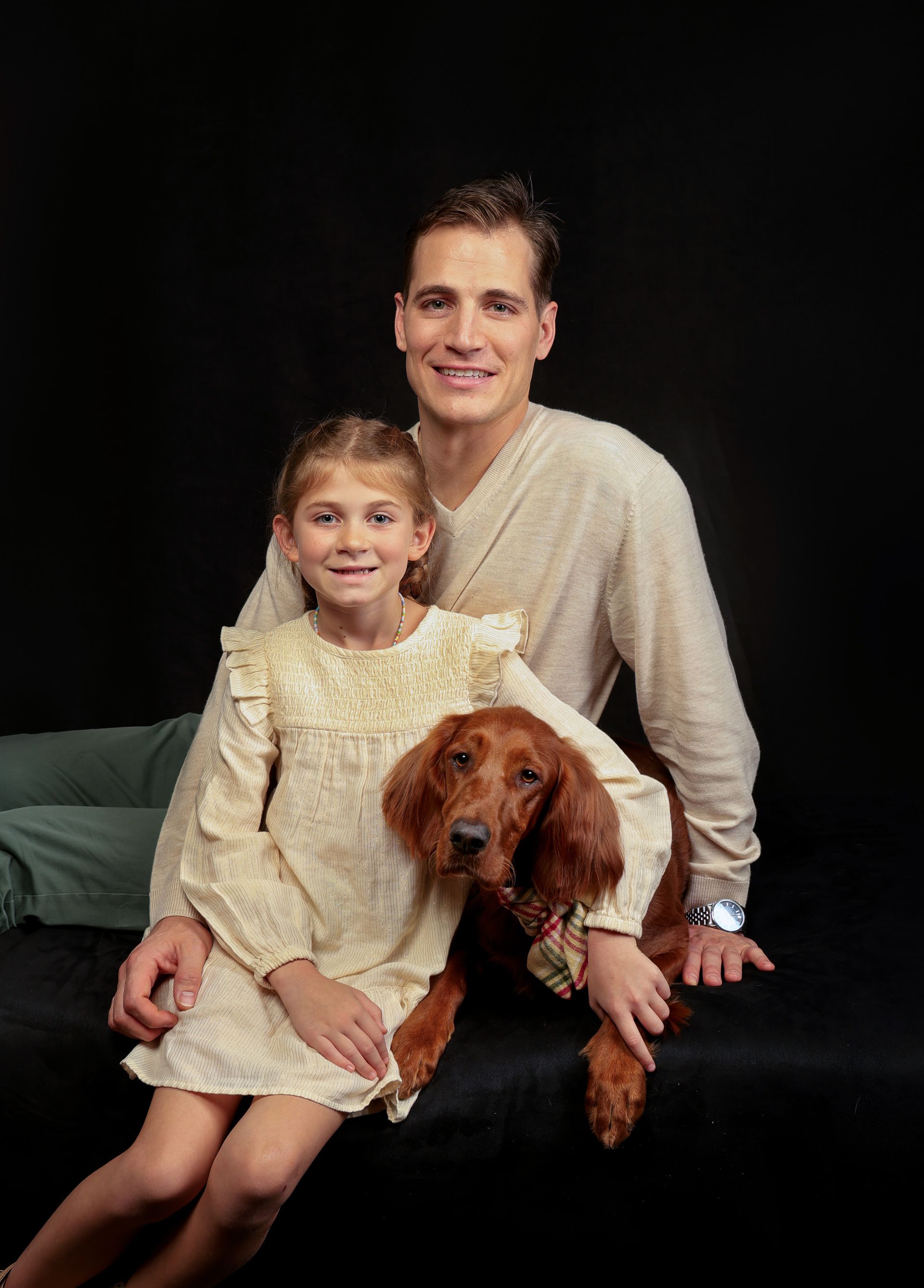 A man and a little girl are sitting on a couch with a dog.