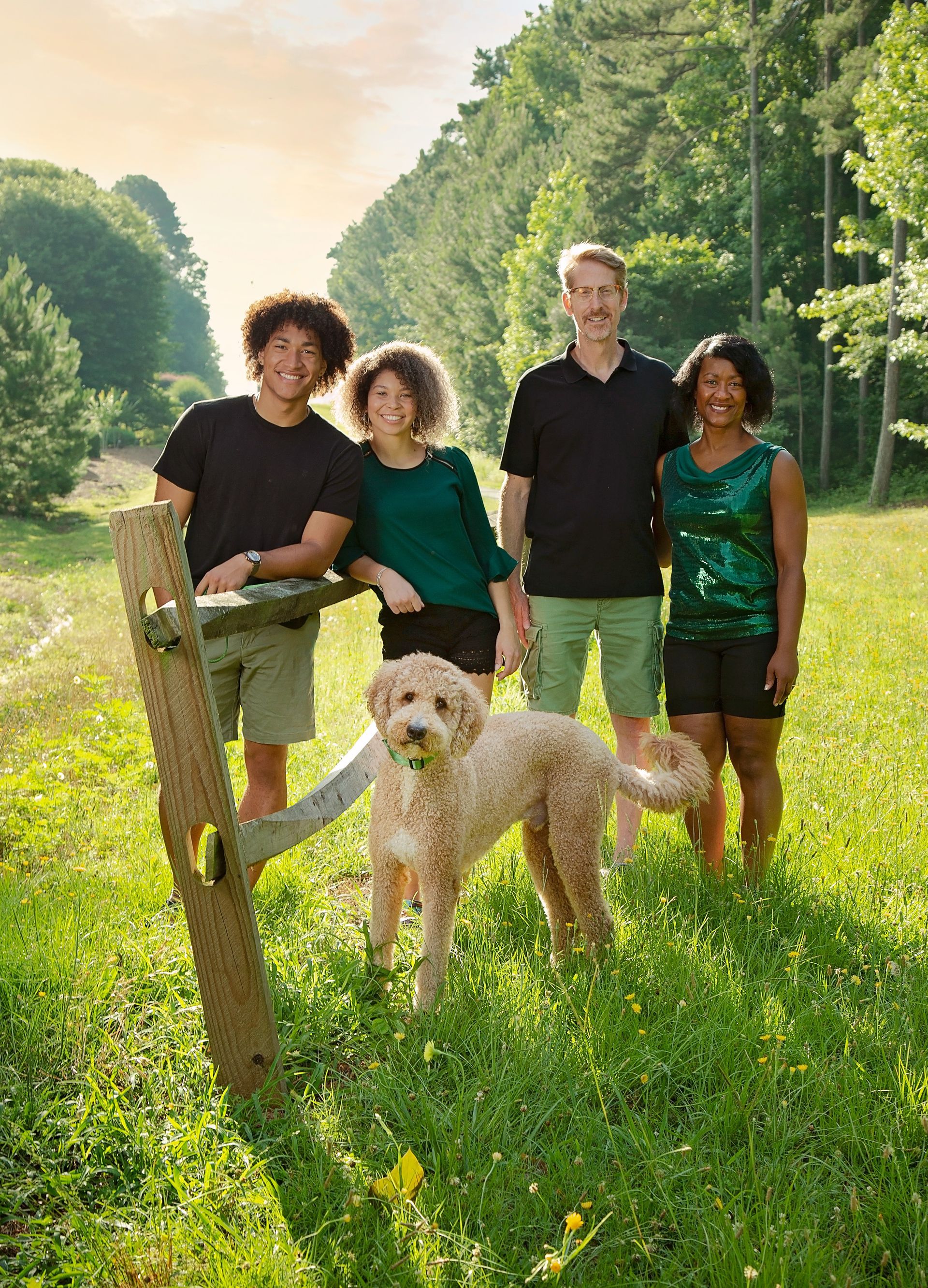A family standing in a field with a dog.
