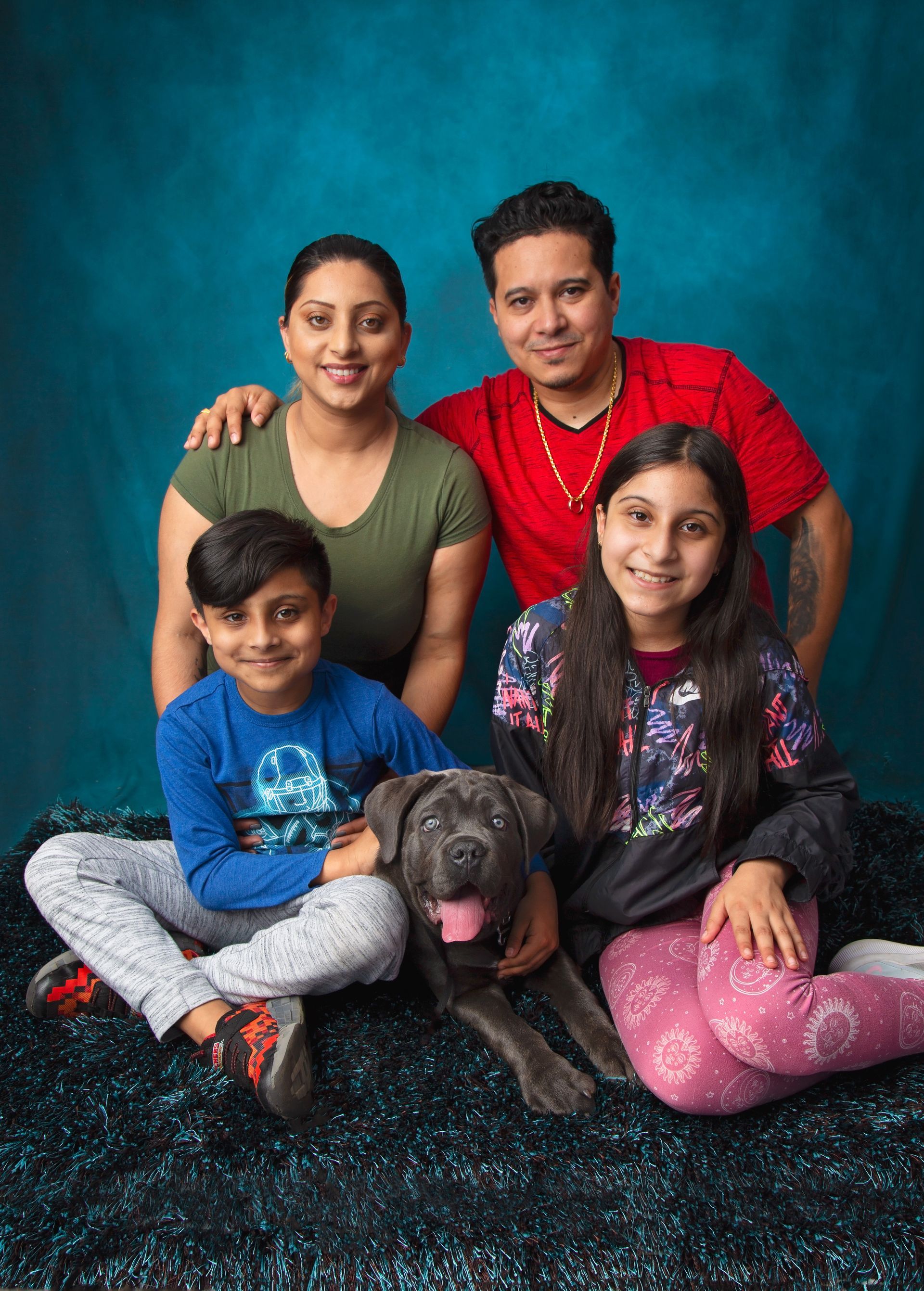 A family is posing for a picture with their dog.