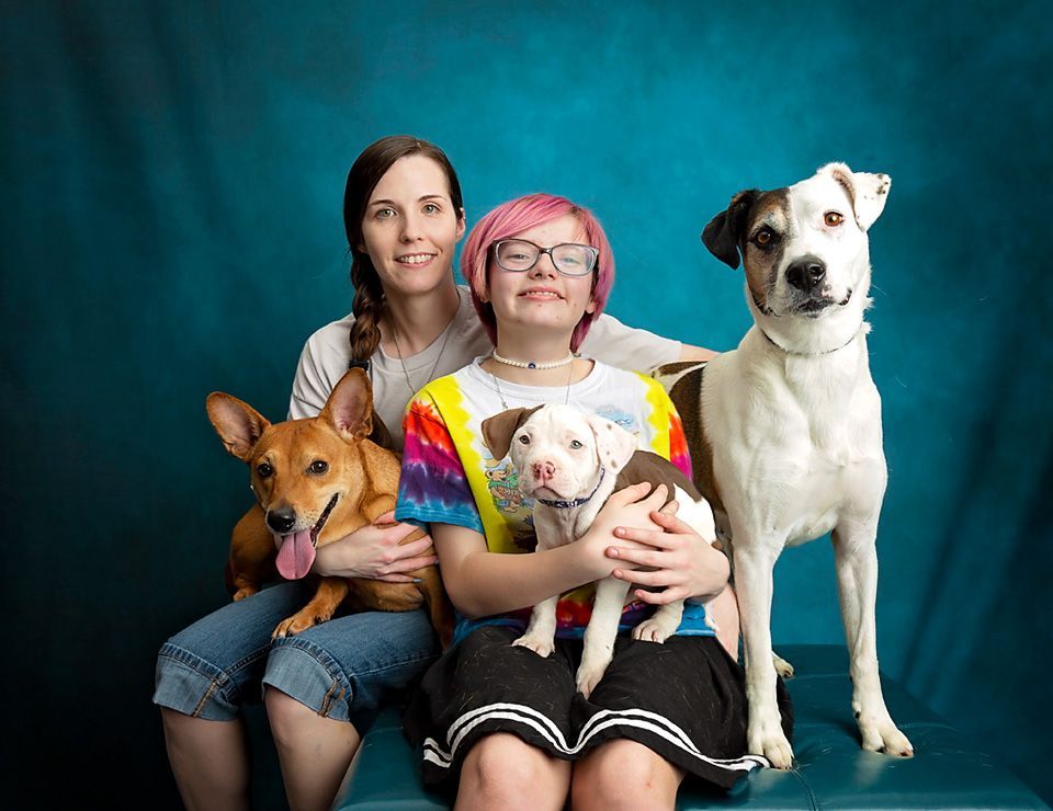 A woman and a girl are posing for a picture with their dogs.