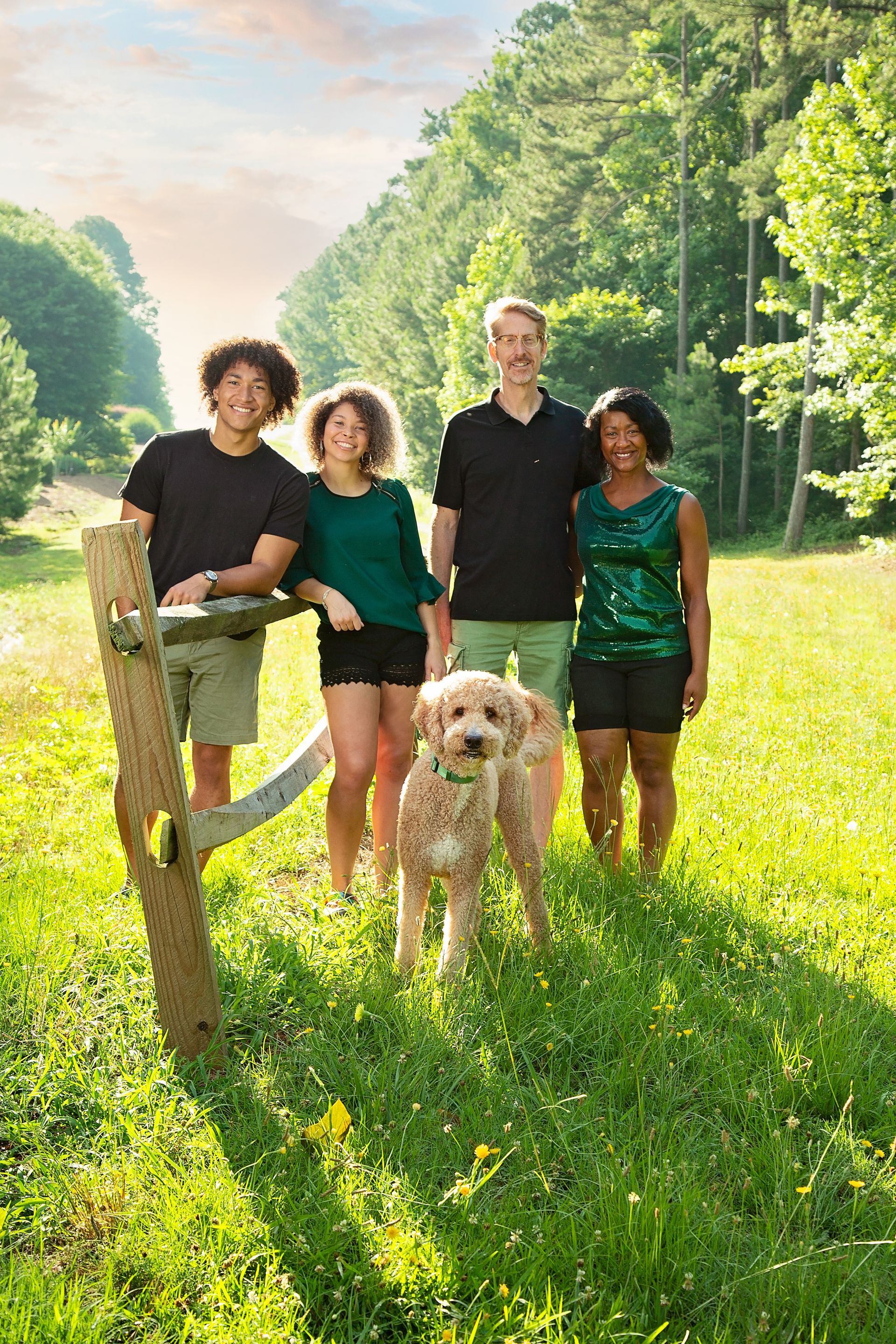 A family standing in a field with a dog.