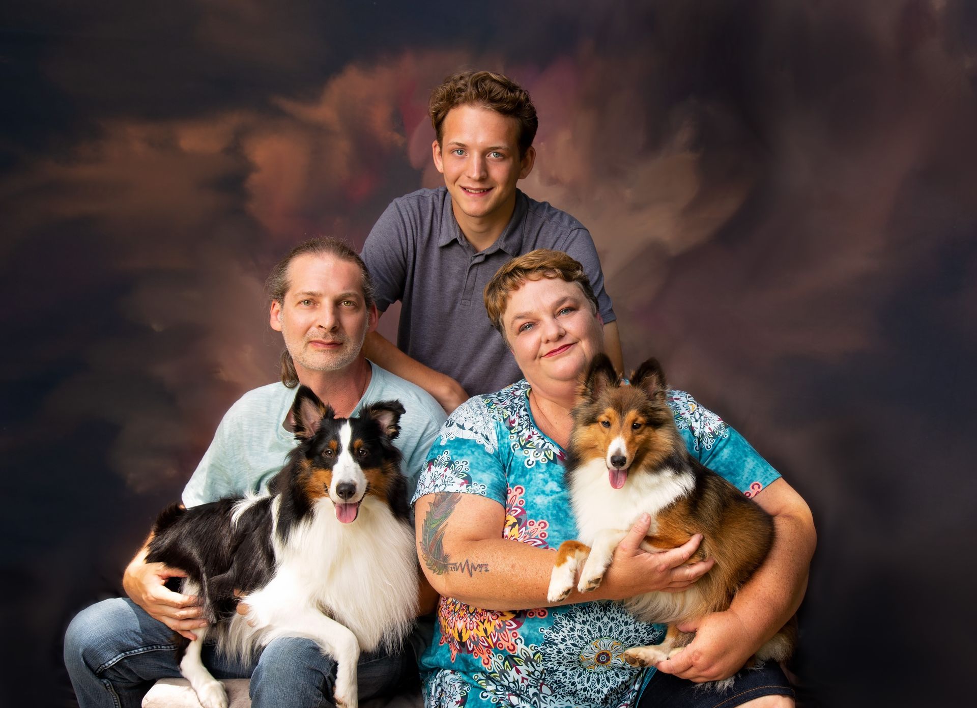 A family is posing for a picture with their dogs.