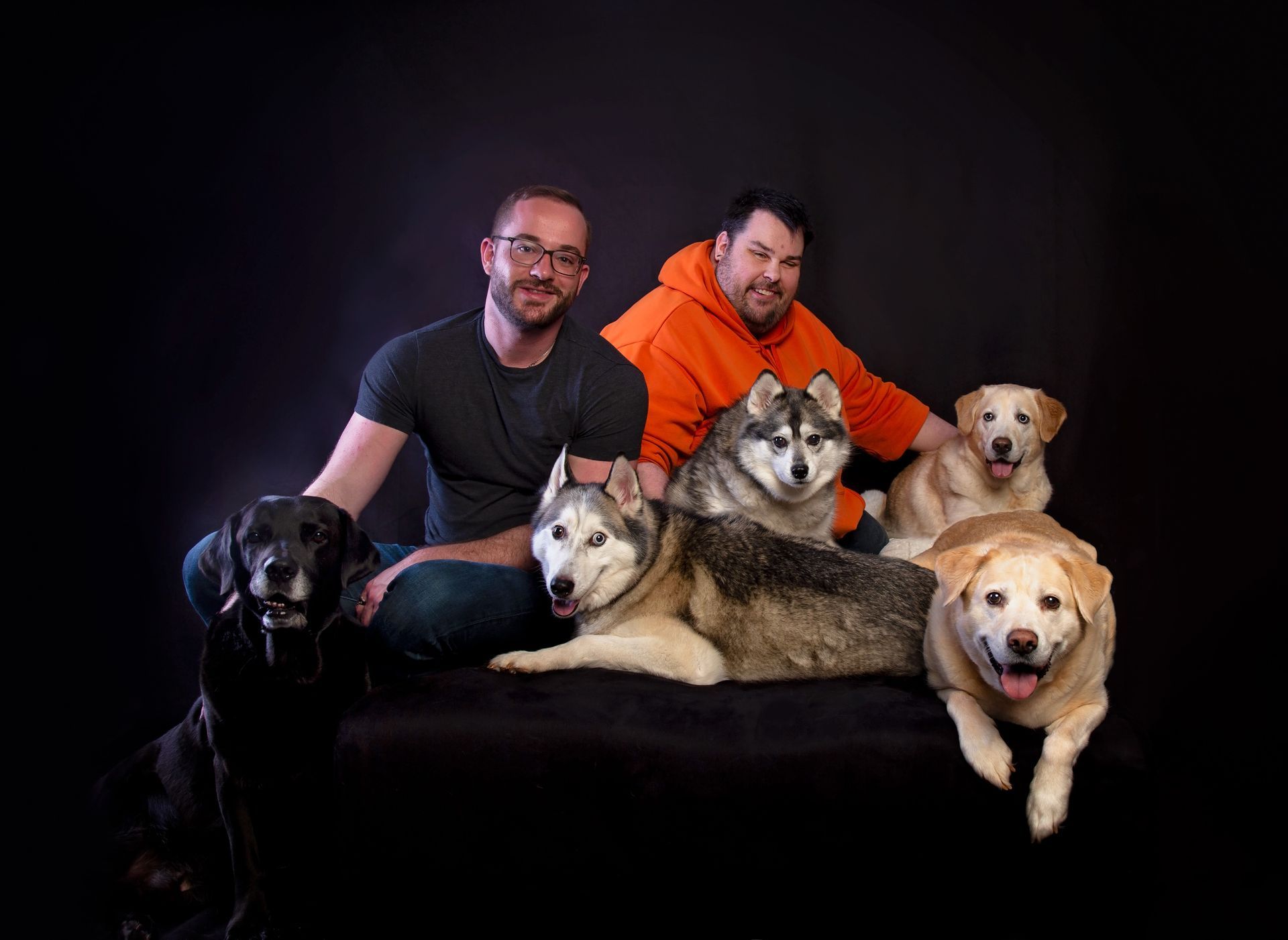 Two men are posing for a picture with their dogs.