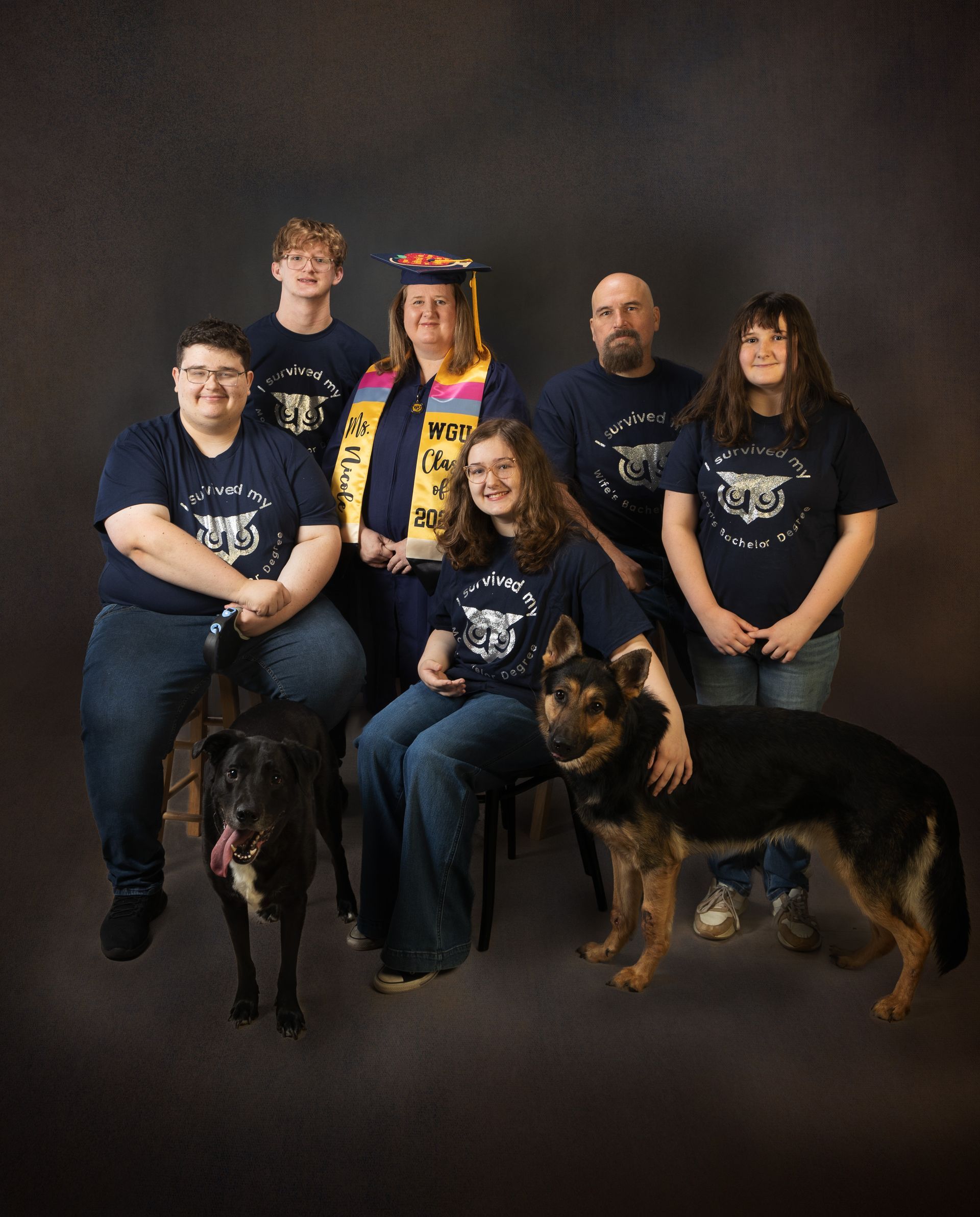 A family posing for a family portrait with their two dogs.