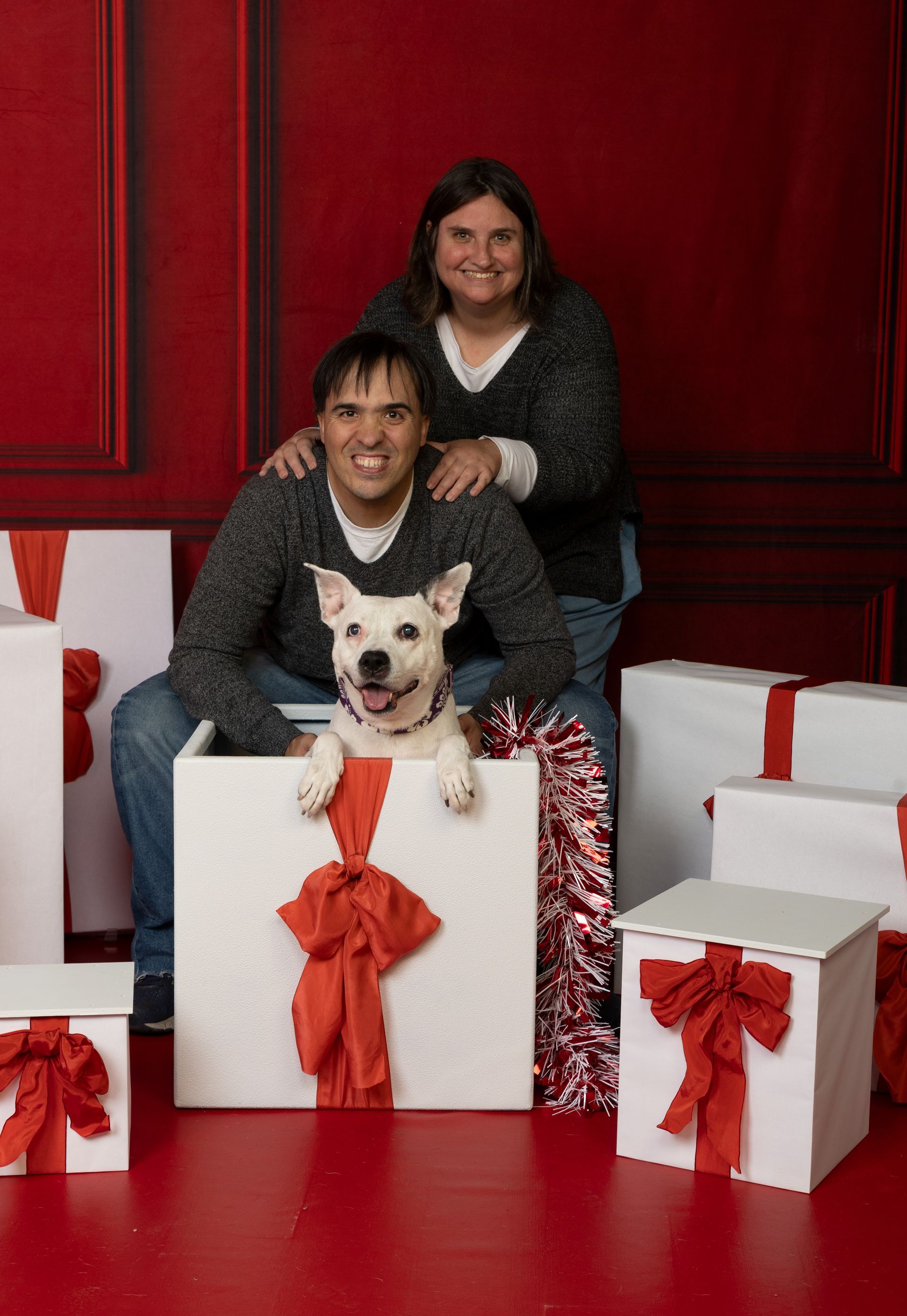 A man and woman are posing for a picture with their dog.