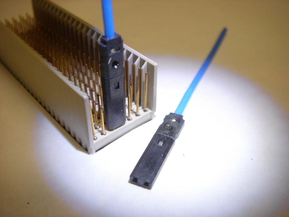 Two blue fiber optic cables with black connectors plugged into a beige connector with gold pins.