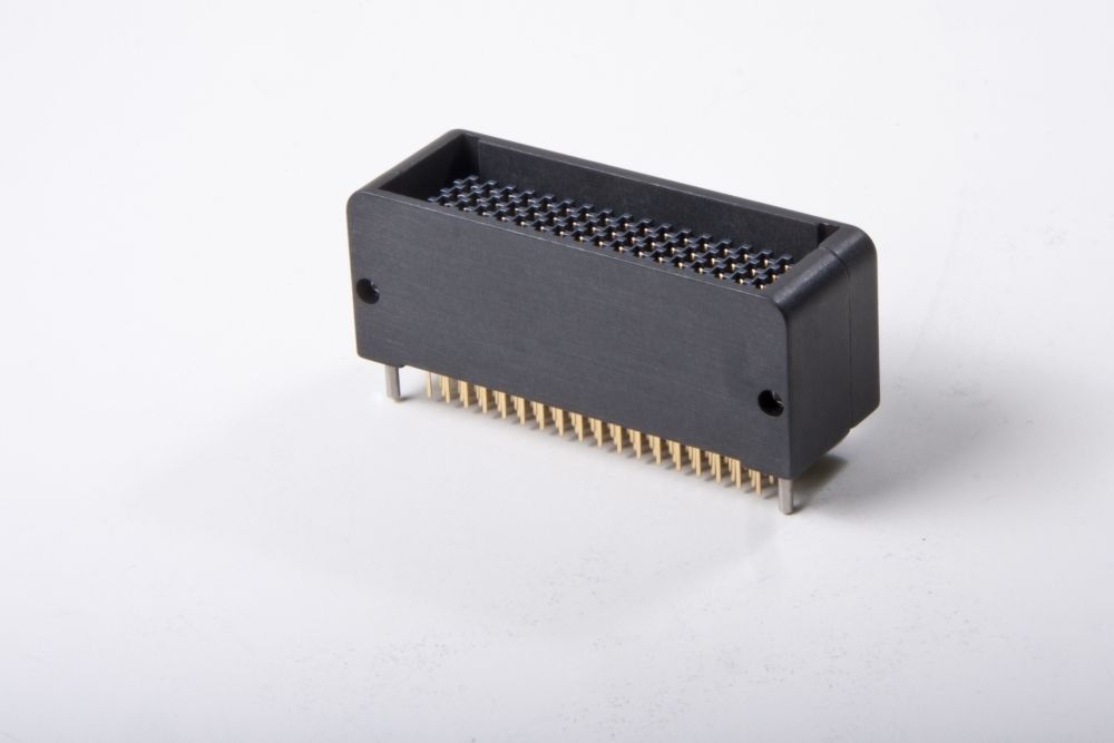 Black electronic connector with pins, angled view, on a white surface.
