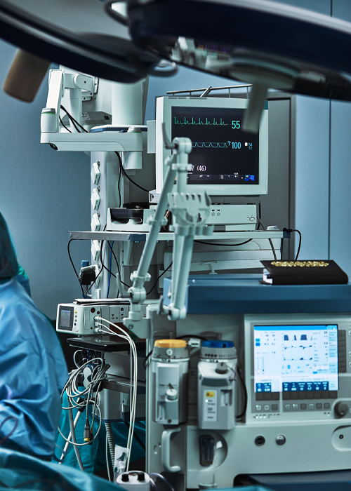 Medical equipment in operating room, monitors displaying vital signs, blue and white.