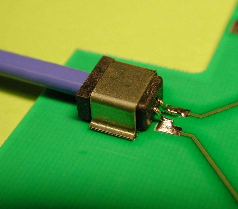 A close-up of a blue wire connected to a metal component soldered onto a green circuit board.